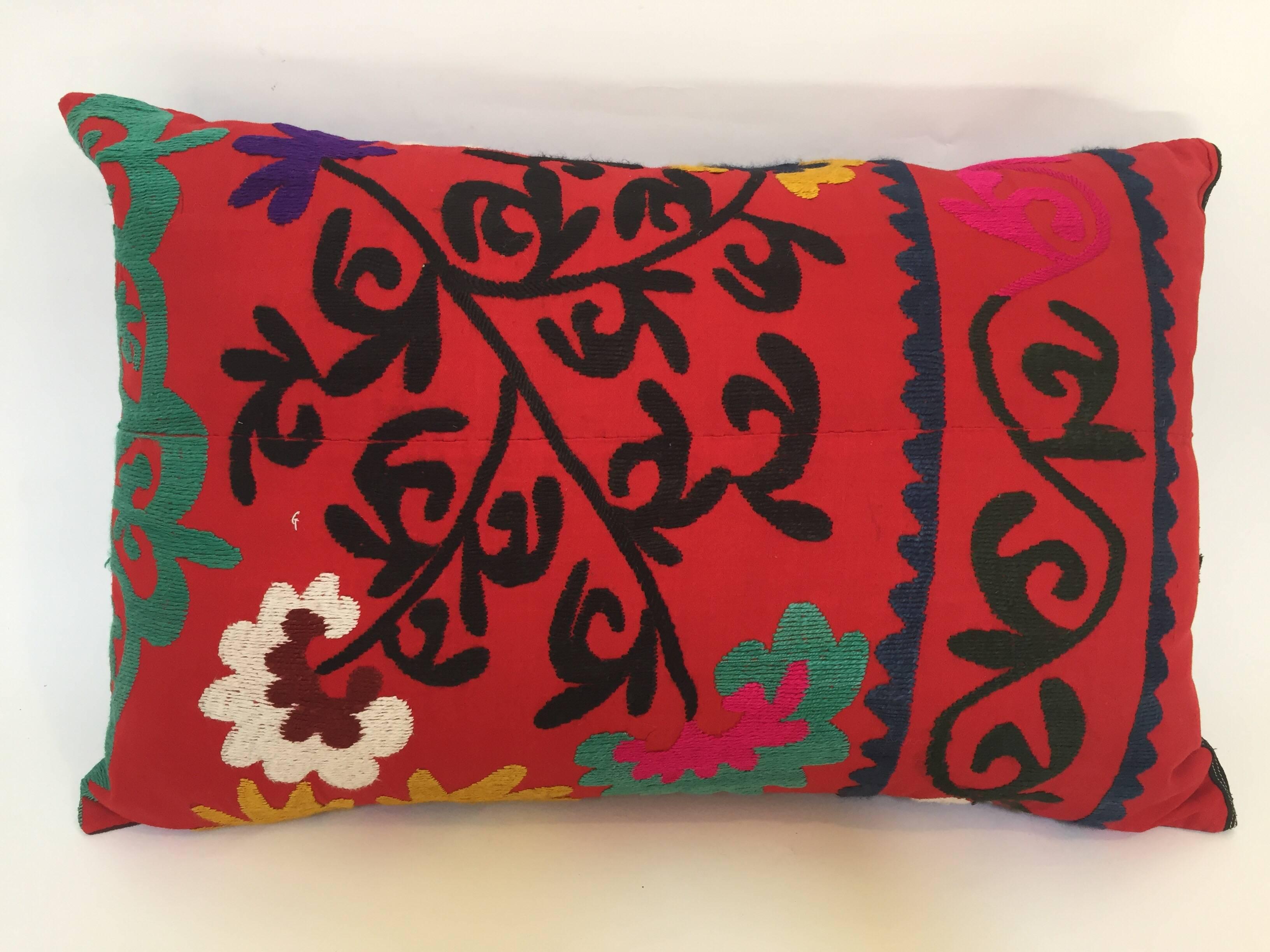 Large vintage colorful Suzani embroidery lumbar pillow red with colorful threads. 
A reddish embroidered pillow with flower motifs in shades of black, red, yellow, white, magenta, kelly green, with linen backing and zipper in the back,. 
The pillow