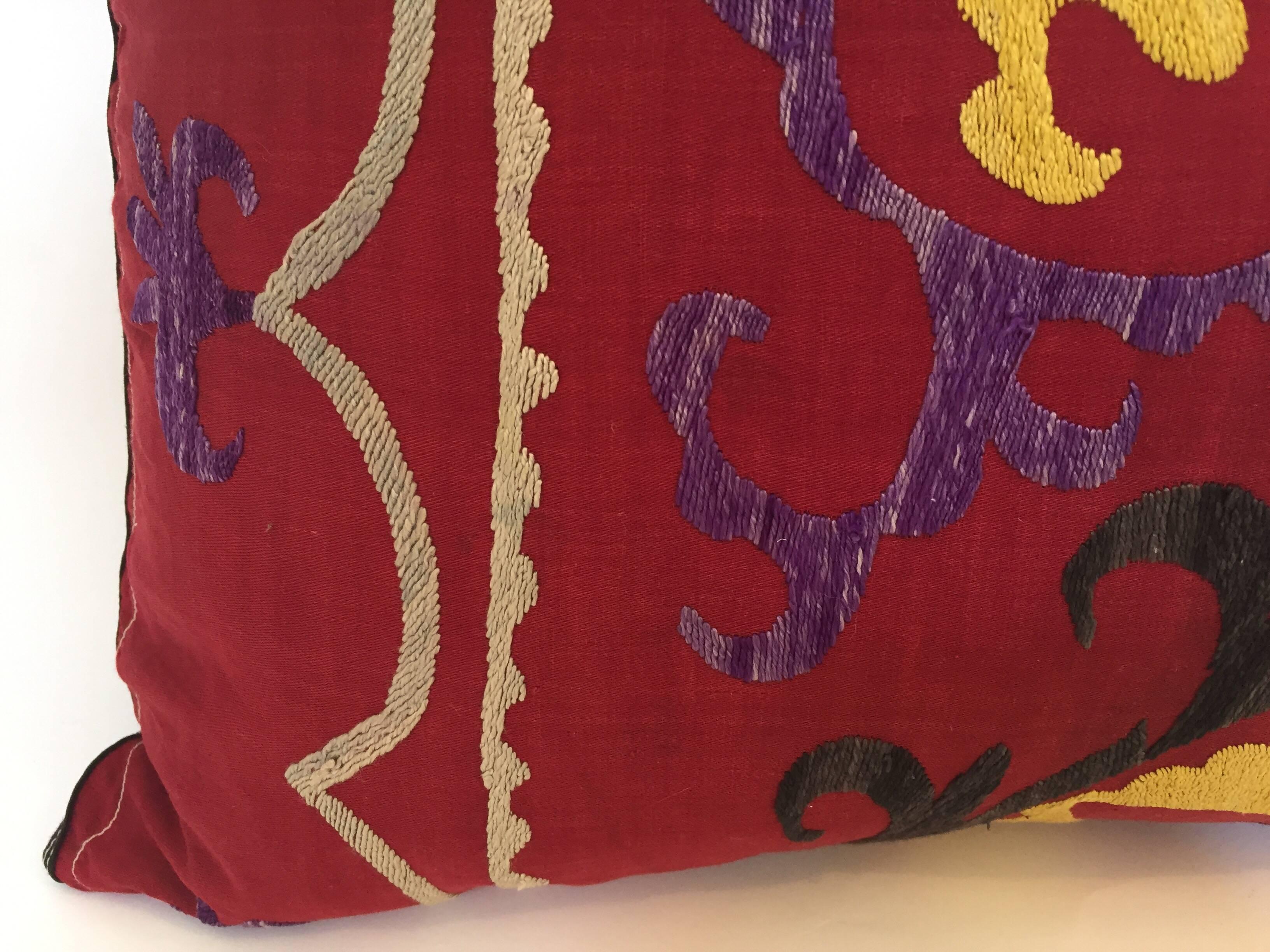 Large vintage colorful Suzani embroidery lumbar pillow red with colorful threads. 
A reddish embroidered pillow with flower motifs in shades of black, red, yellow, white, magenta, with linen backing and zipper in the back,. 
The pillow is made out