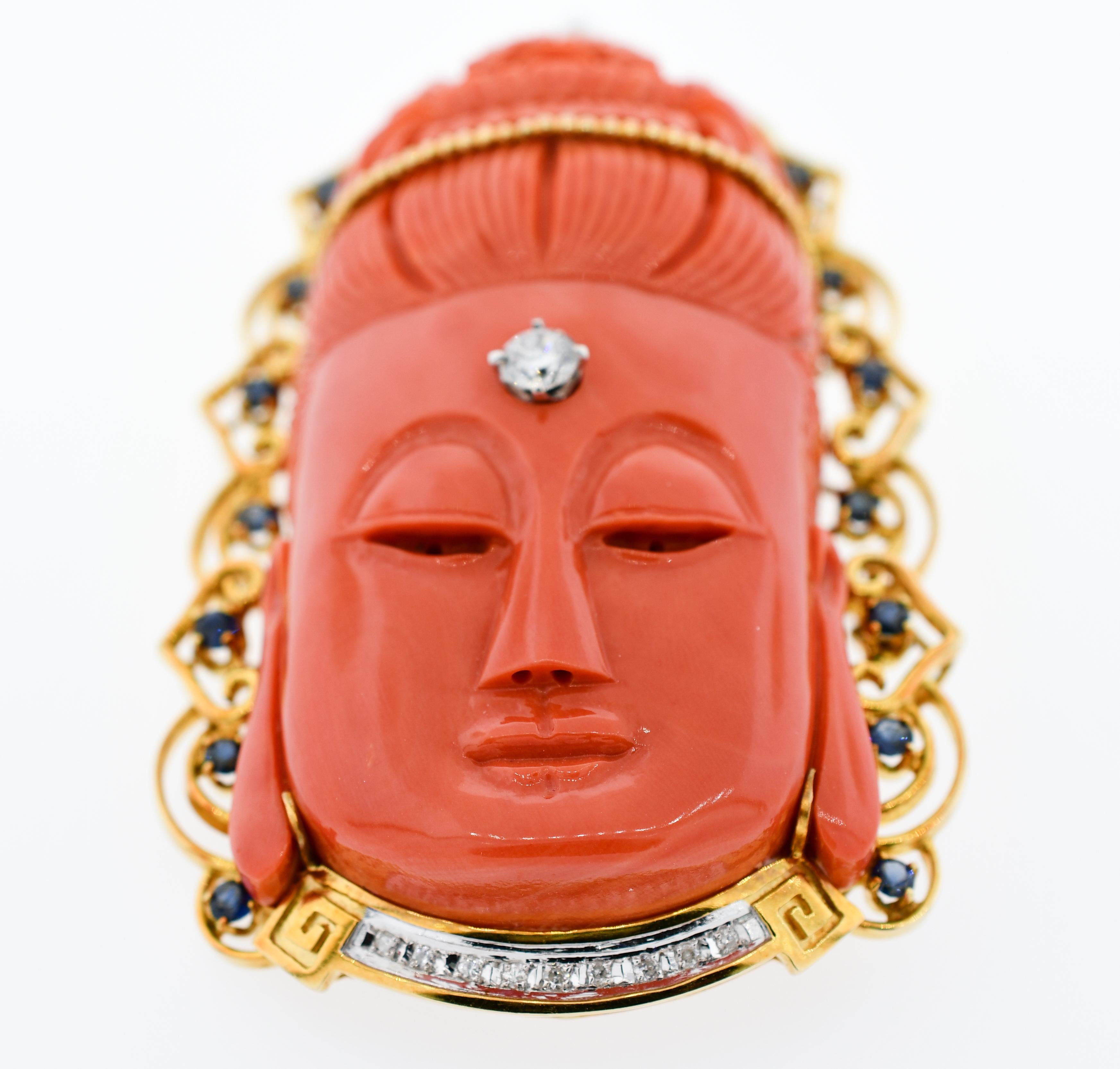 Absolutely stunning color and vitreous shine, beautifully detailed hand carved coral.  The Buddah is framed with a 14 karat yellow gold decorative fringe which is accented by nineteen (19) round blue sapphires and sixteen (16) round brilliant cut