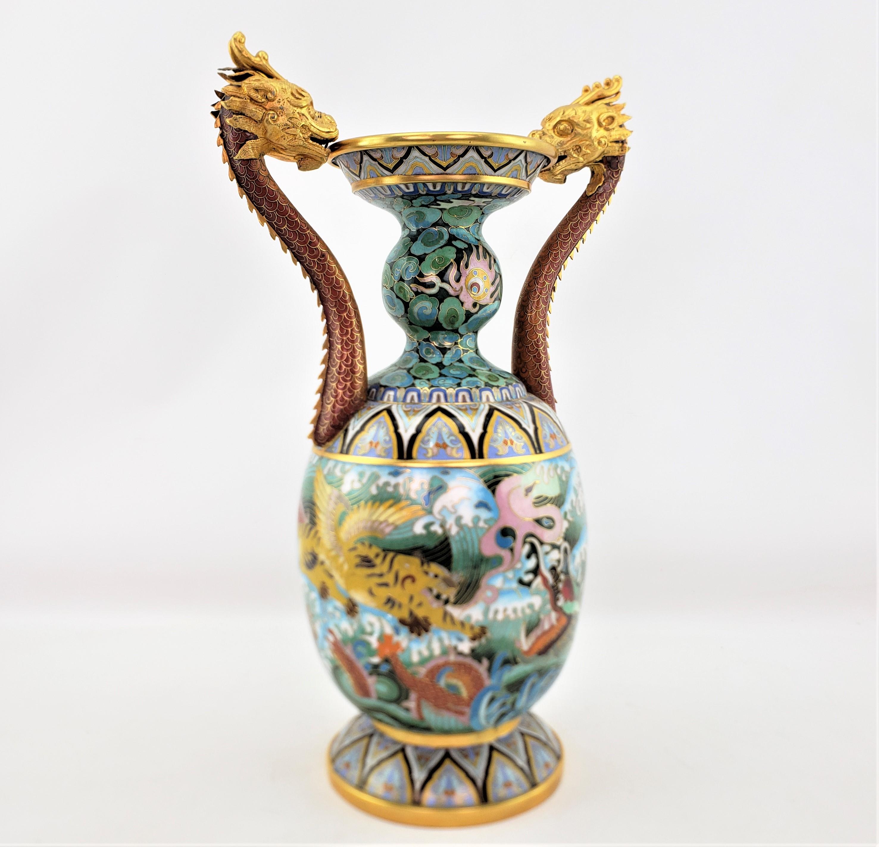 This large vintage cloissone vase is signed by an unknown maker, and originated from China dating to approximately 1980 and done in a Chinese Export style. The vase is composed of brass with ornately cast and gilt finished Imperial Dragon handles.