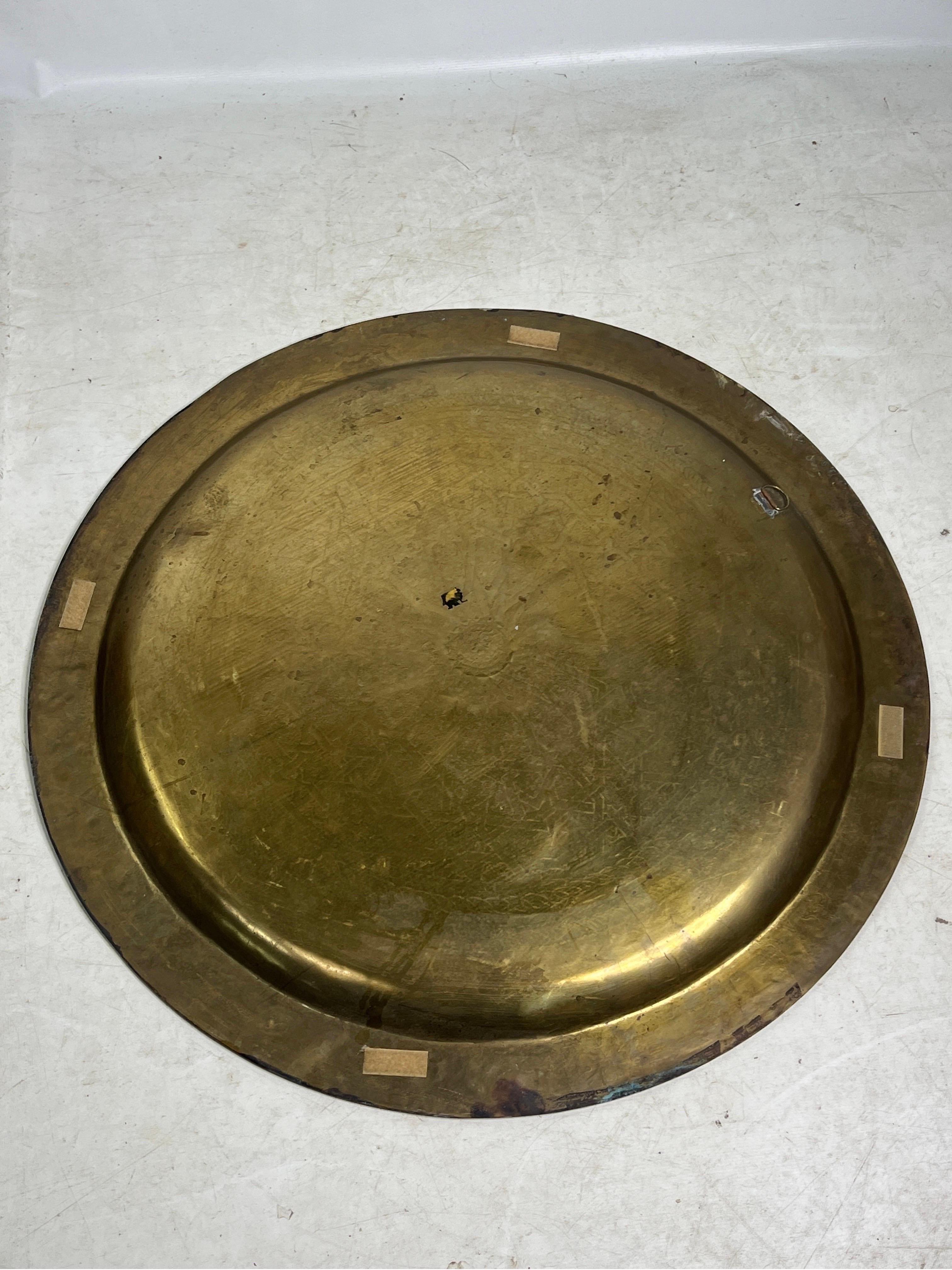 This vintage round solid brass tray is a beautiful decorative piece that is now available for sale. It features an exquisite design that adds a touch of elegance to any space.
