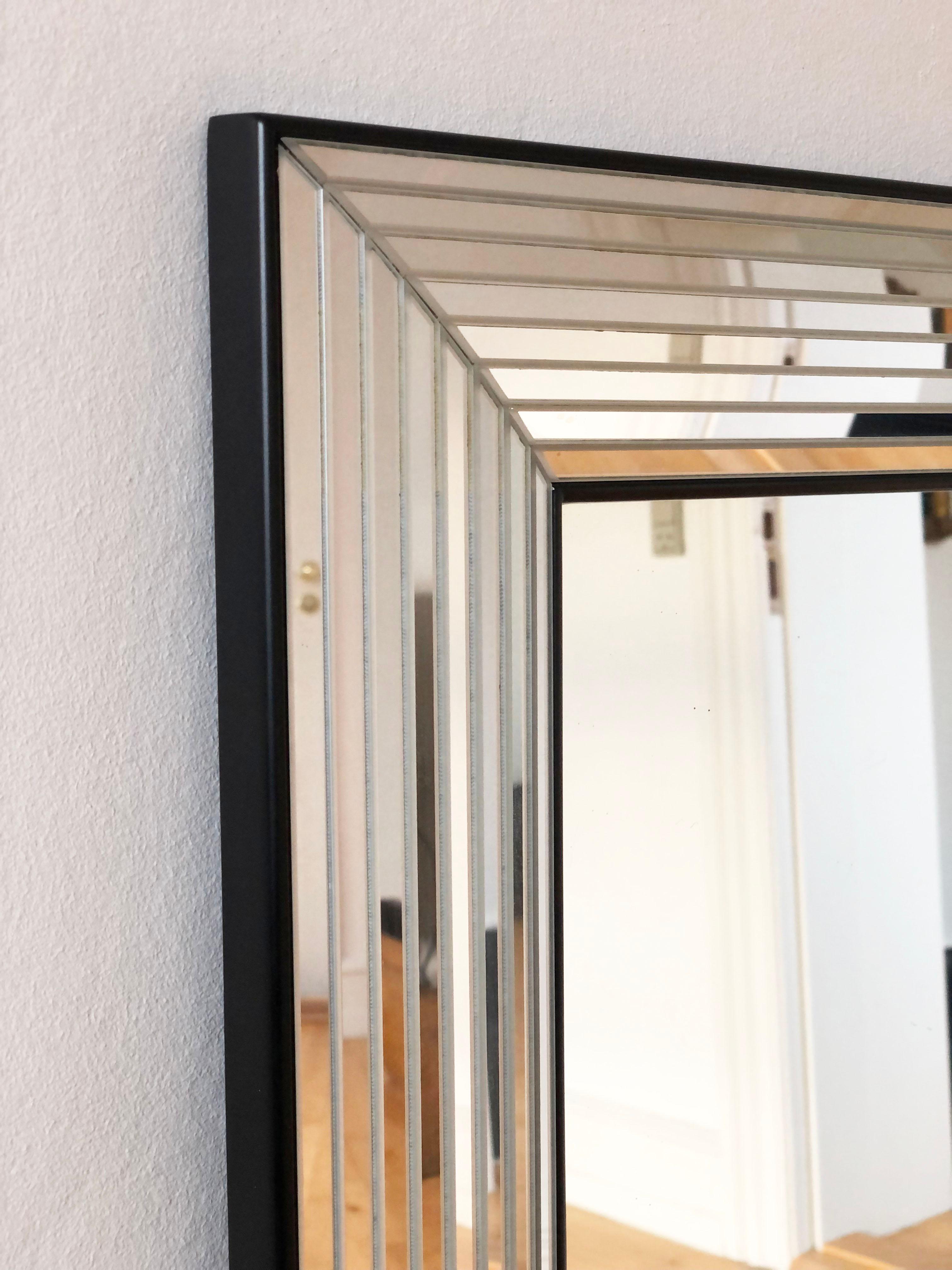 Specchio rettangolare di Deknudt, realizzato in Belgio negli anni Novanta. La cornice è caratterizzata da un design in vetro a forma profonda che attraversa tutta la sua larghezza, conferendole un aspetto unico ed elegante. Una striscia nera e