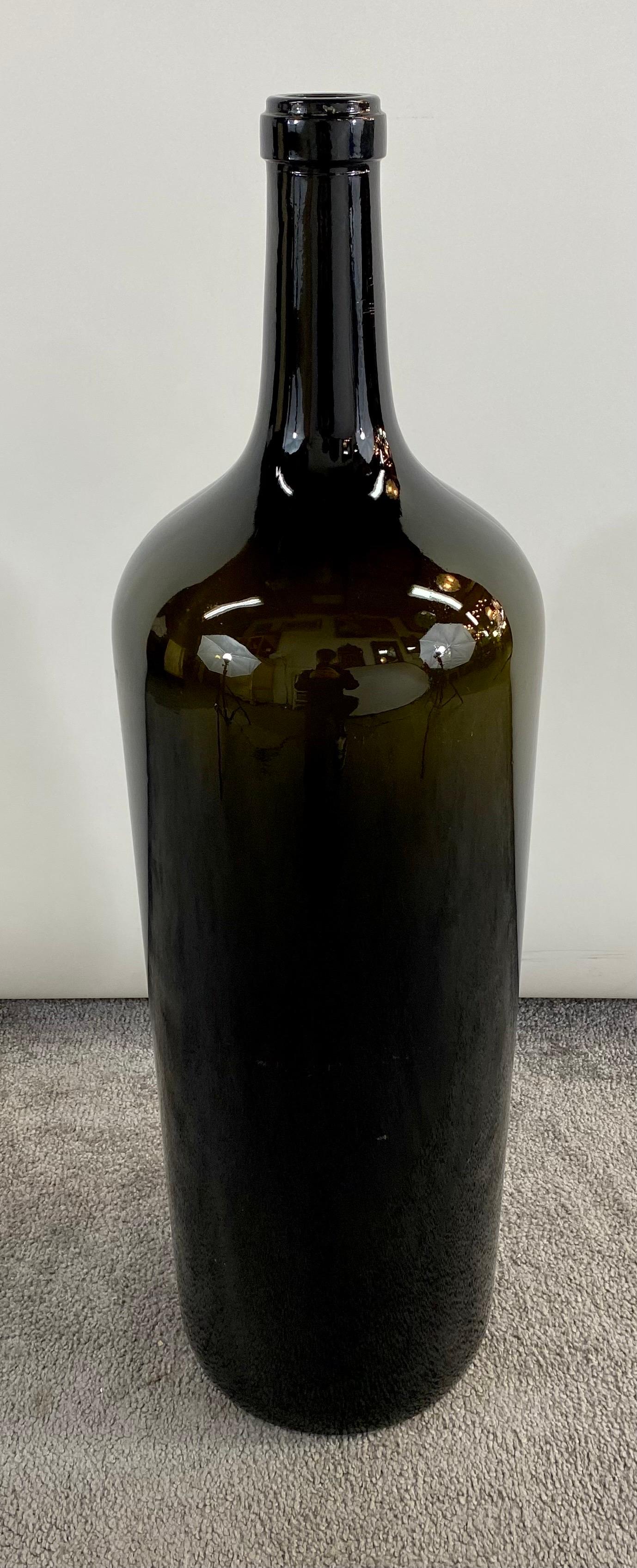 A large pair of vintage dark green blown glass Demijohn style bottles of wines. The bottles are sturdy and very decorative.  Embellish you room or wine cellar with these pair of large wine bottles or use them as urns to show your favorite
