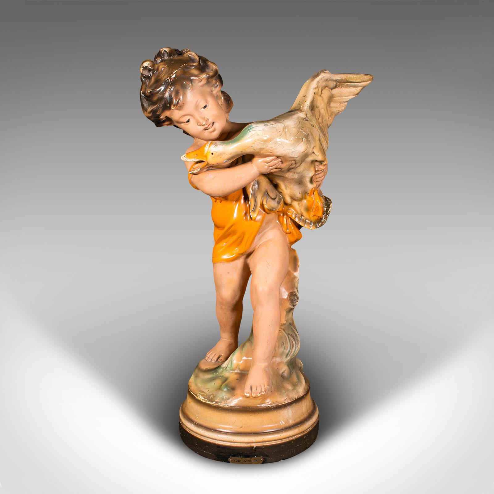 This is a large vintage display figure. An English, plasterwork decorative girl with duck ornament, dating to the Art Deco period, circa 1930.

A chaotic moment, with the unruly duck scrabbling in the girl's arms
Displays a desirable aged patina and