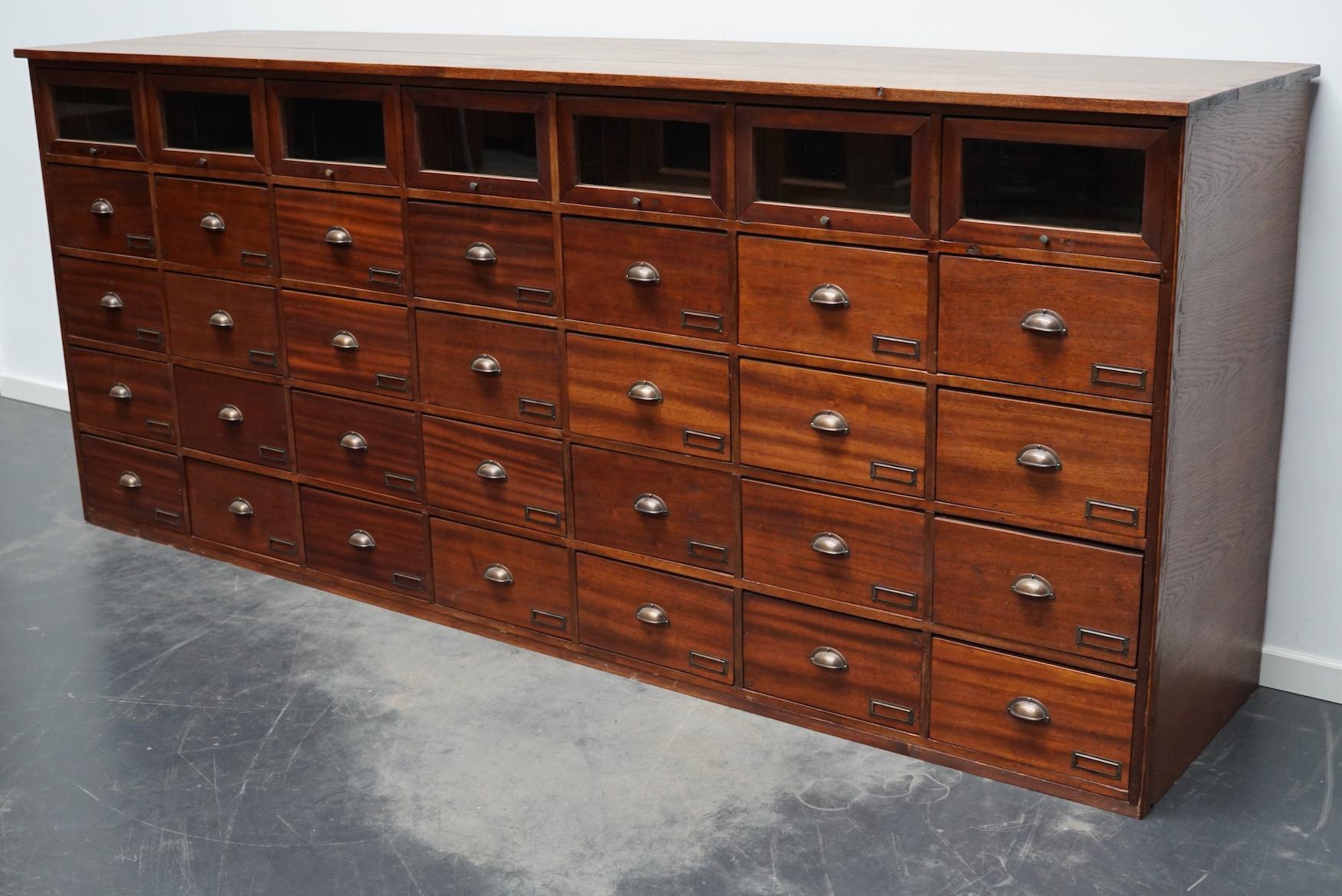 This haberdashery cabinet was produced during the 1940s in the Netherlands. It features 35 drawers in mahogany, some with glass fronts and with brass handles / name card holders. It was originally used in a shop for sewing supplies and fabrics in