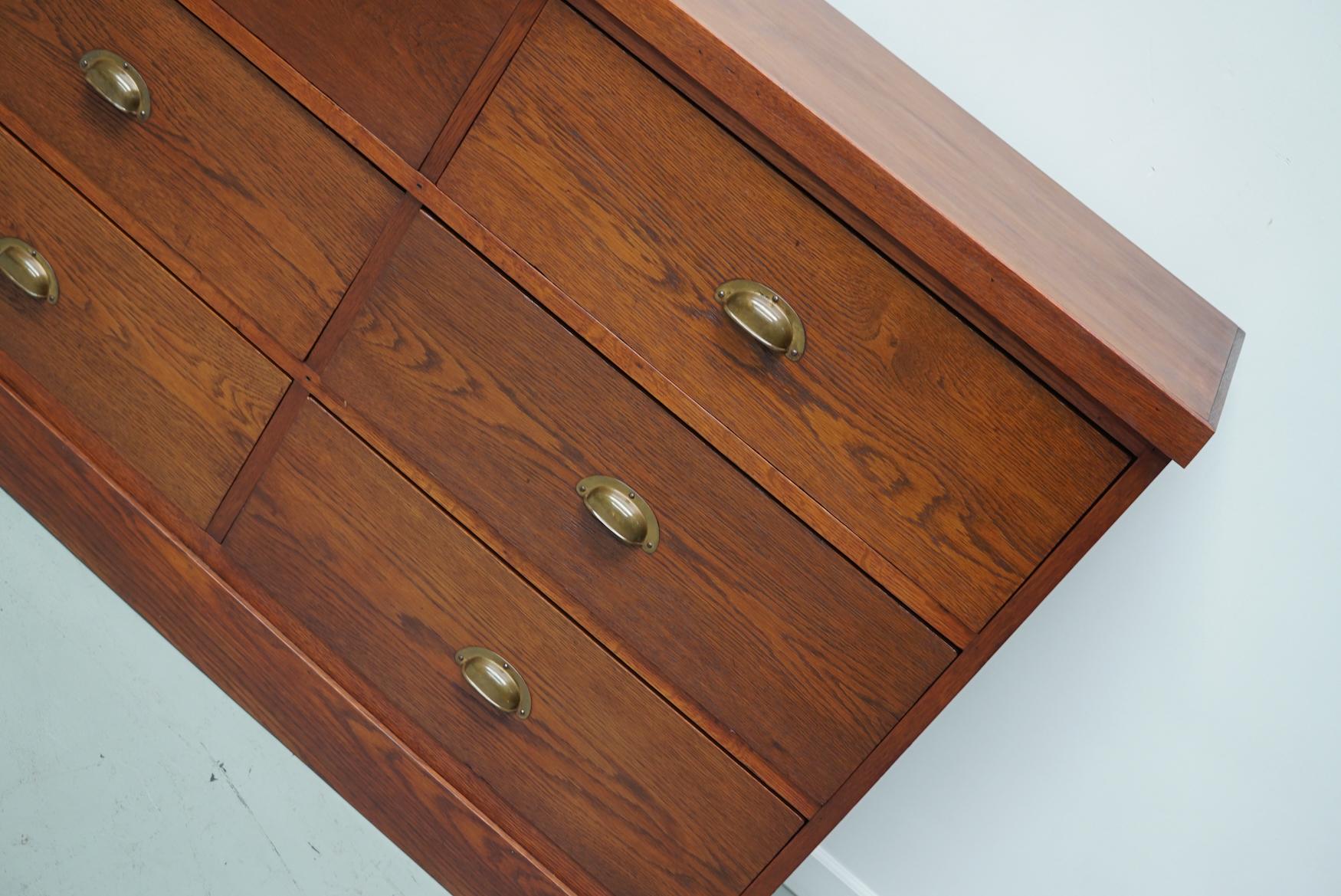 Cette armoire a été fabriquée dans les années 1930 aux Pays-Bas. Il comprend 12 grands tiroirs fonctionnels en chêne avec des ferrures en laiton. Les dimensions intérieures des tiroirs sont les suivantes : D 32 x L 61 x H 19,5 cm.