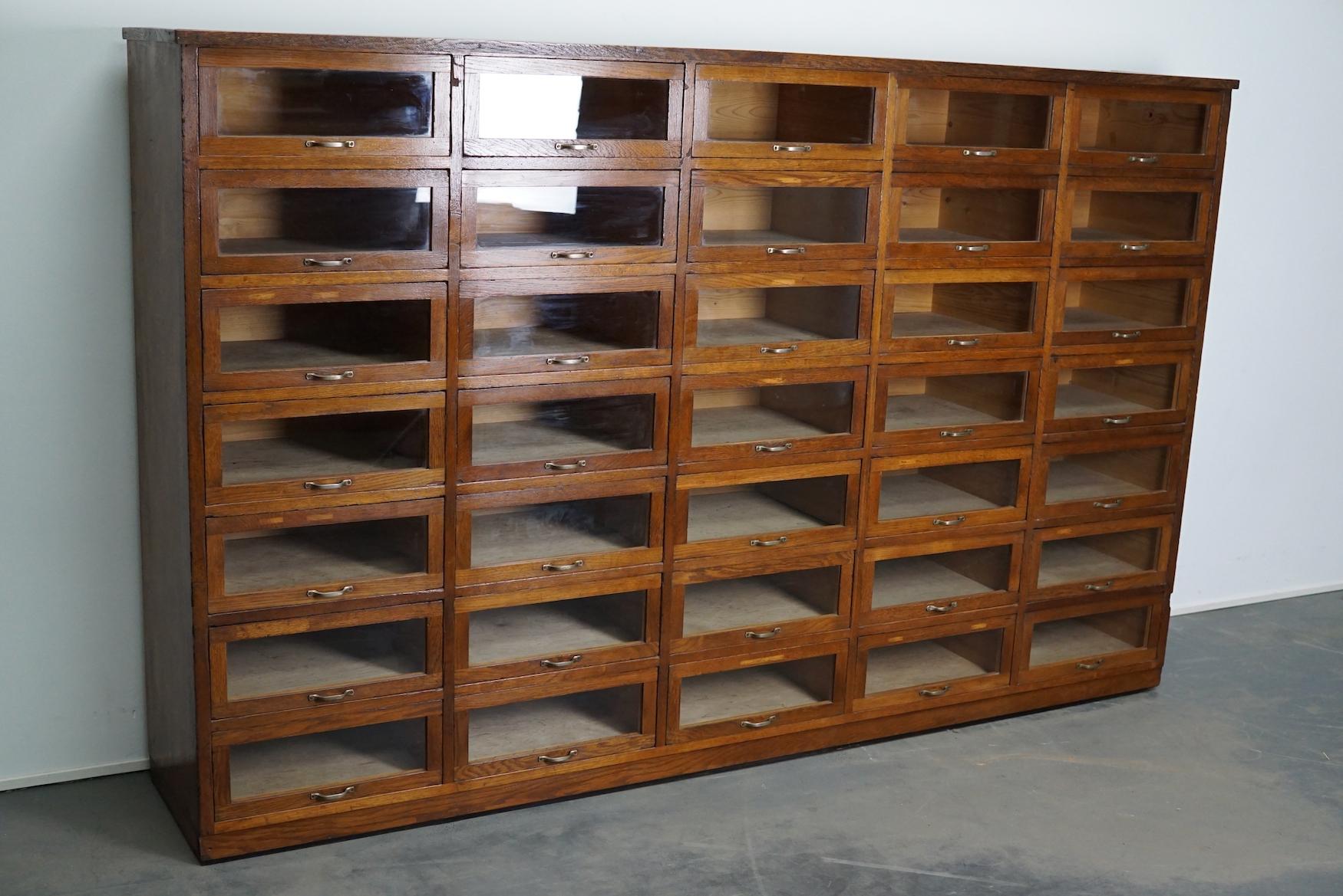 This haberdashery cabinet was produced during the 1930s in the Netherlands. This piece features 35 drawers in oak with glass fronts and metal handles. It was originally used in a shop for sewing supplies and fabrics in Amsterdam. The interior