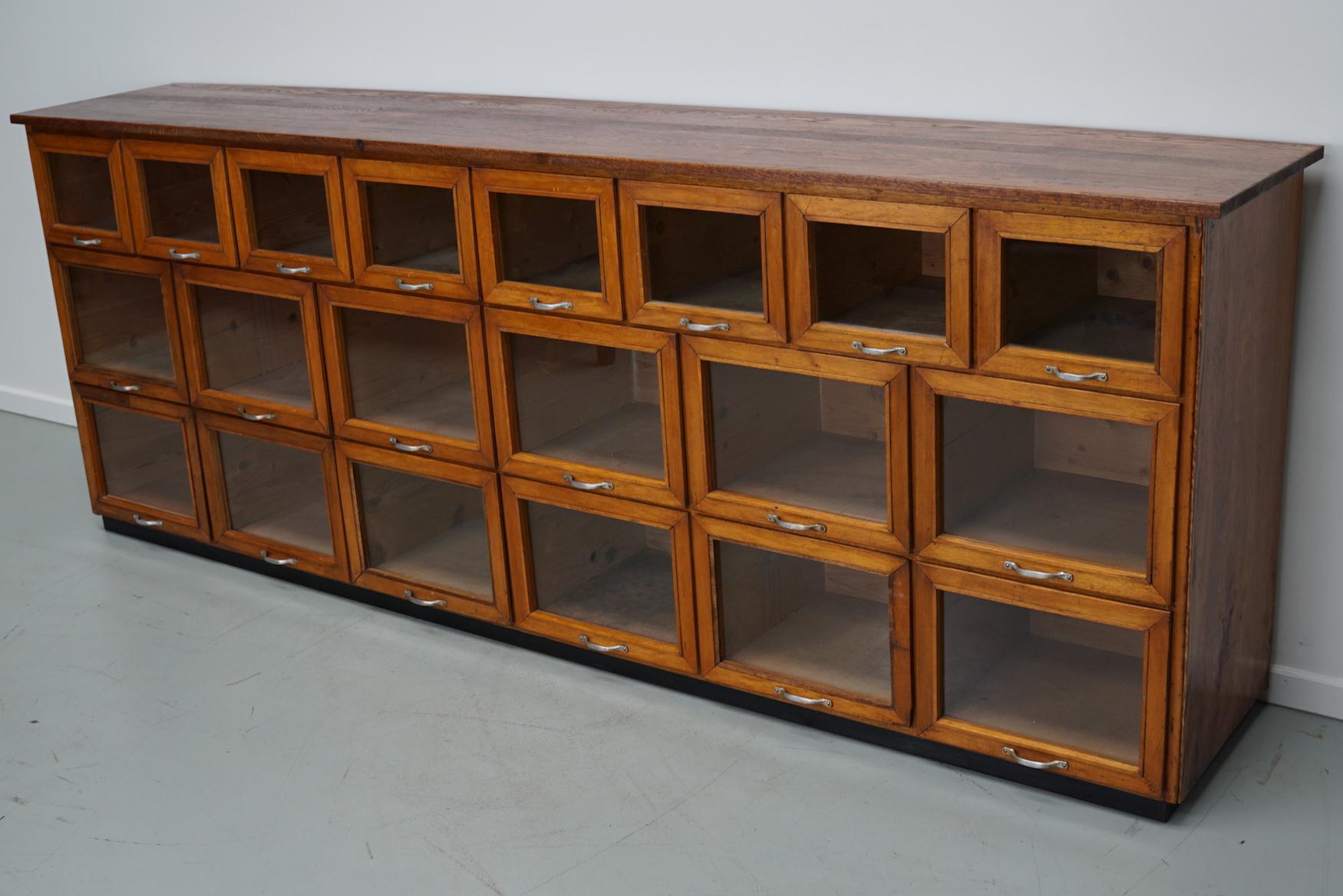 This haberdashery cabinet was produced during the 1950s in the Netherlands. It features 20 large drawers in oak with glass fronts and metal handles. It was originally used in a warehouse for plant seeds in the city of Delft. The interior dimensions