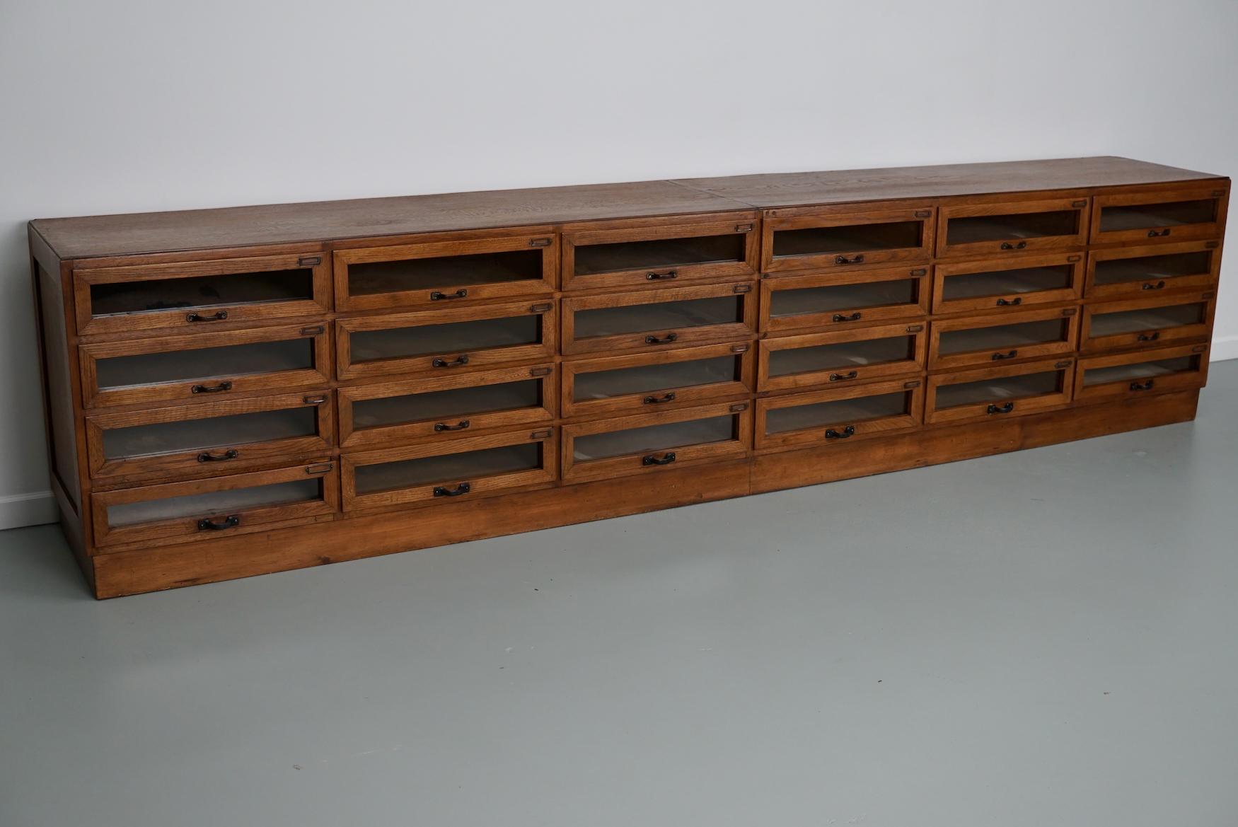 This haberdashery cabinet was produced during the 1950s in the Netherlands. It features 24 large drawers in oak with glass fronts and metal handles. The interior dimensions of the drawers are: DWH 40 x 45 x 10.5 cm.