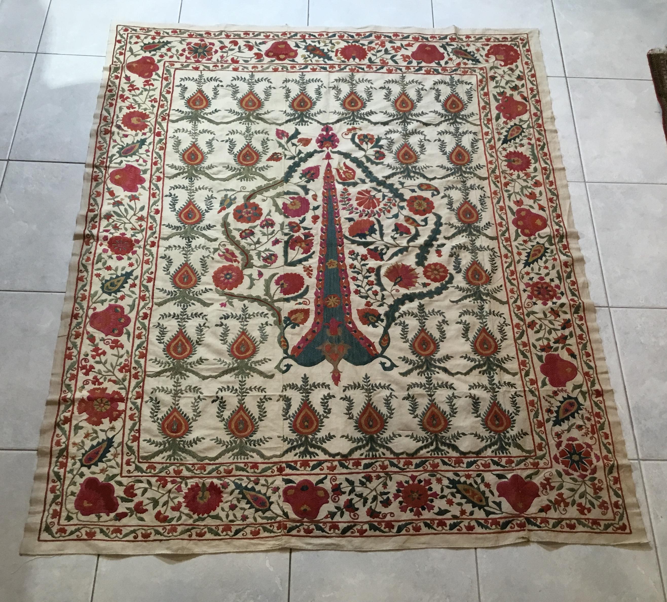 Beautiful artisan Suzani textile made of hand embroidery silk, of floral and vine motifs, all around one way center piece on cream color handcrafted background. Could use as a tapestry, wall hanging or on sofa chair or bed.