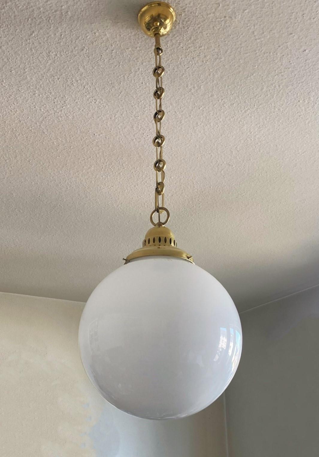 A very elegante Country House hand-blown opaline glass pendant light  with brass gallery, France, circa 1950s.
Large opaline glass ball with brass shade holder with pierced details for light projection, beautiful brass chain and canopy. With a