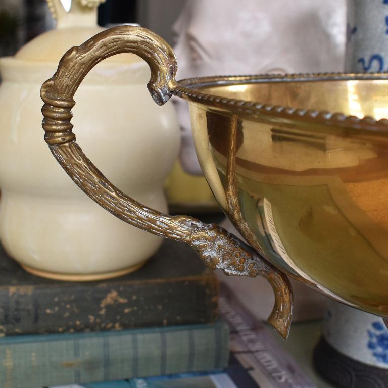 A large beautiful brass compote, trophy, or loving cup. Made in India, this piece will be perfect for a mantle, as a centerpiece or as a planter or fruit bowl. The base is square and features four legs which are covered in grapes. There are two