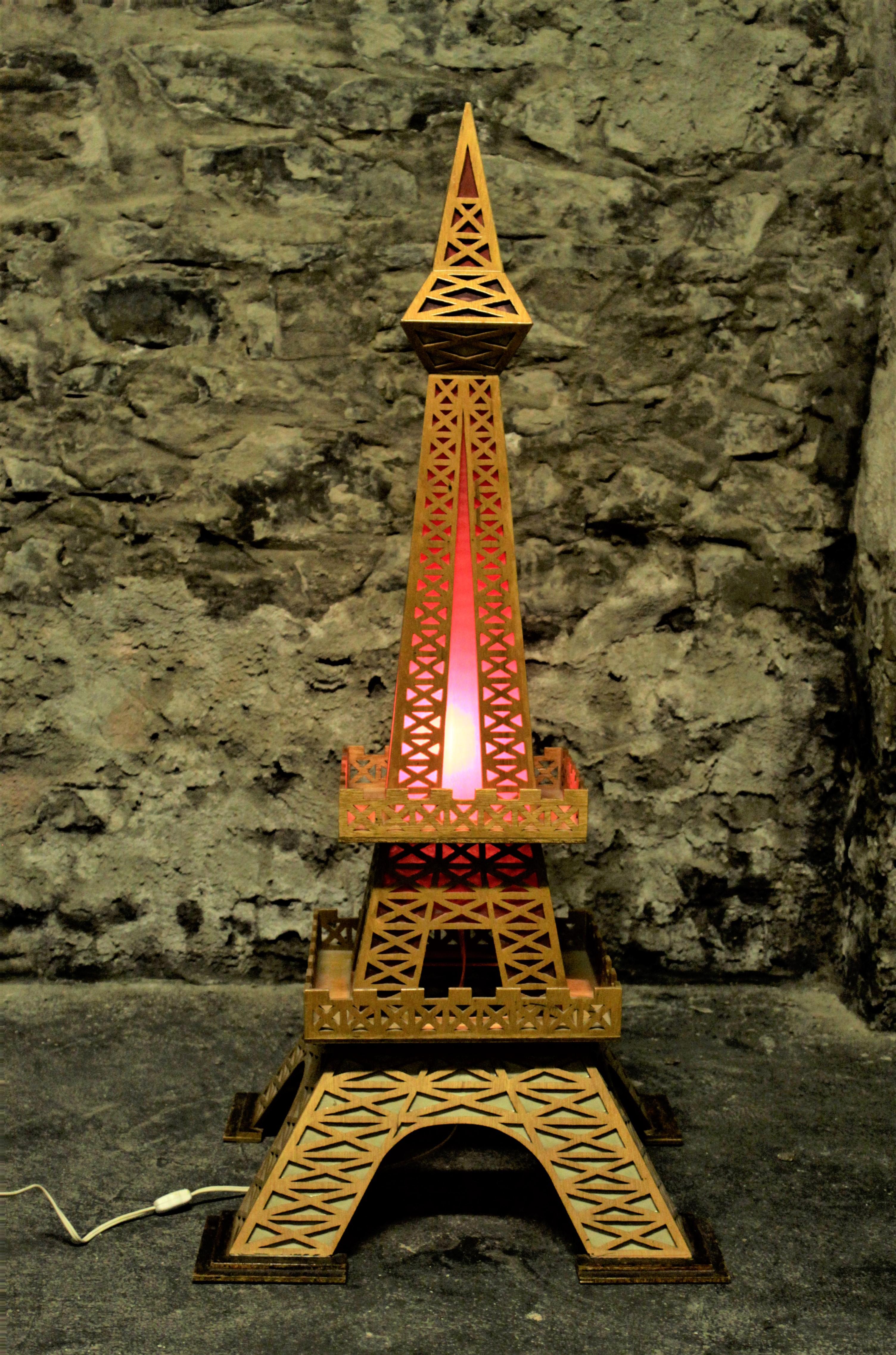 This vintage and substantial Folk Art rendering of the Eiffel Tower was made during the 1970's, presumably in the United States and lights up, providing a subtle red glow to accent the piece and the space. The tower is composed of intricately cut