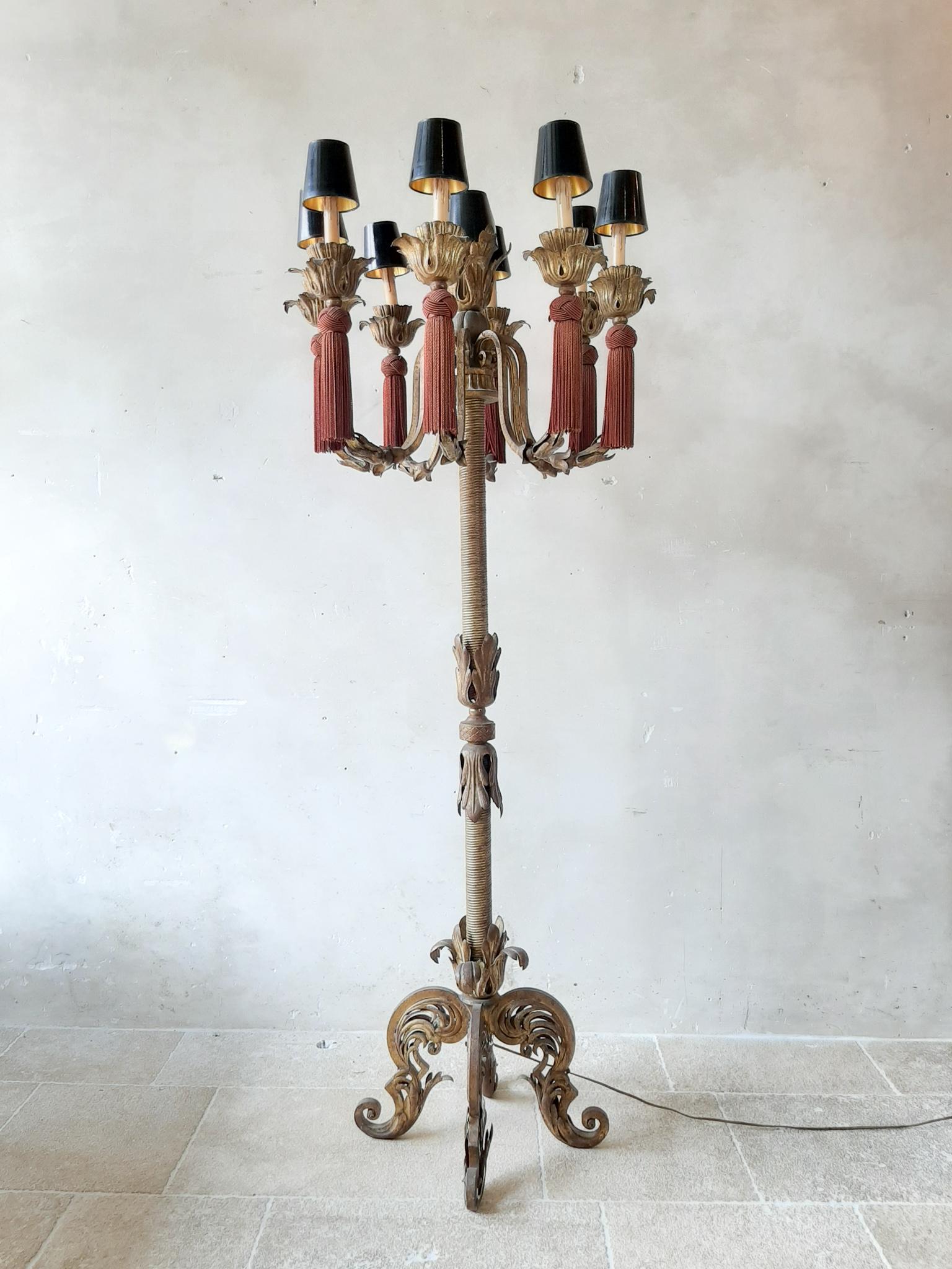 A large, richly decorated, vintage French floor lamp, antique design. The heavy metal armature, the shaft and the base are covered with golden patinated brass and provide the warm color in 'old' gold. The floor lamp has 9-light points with black