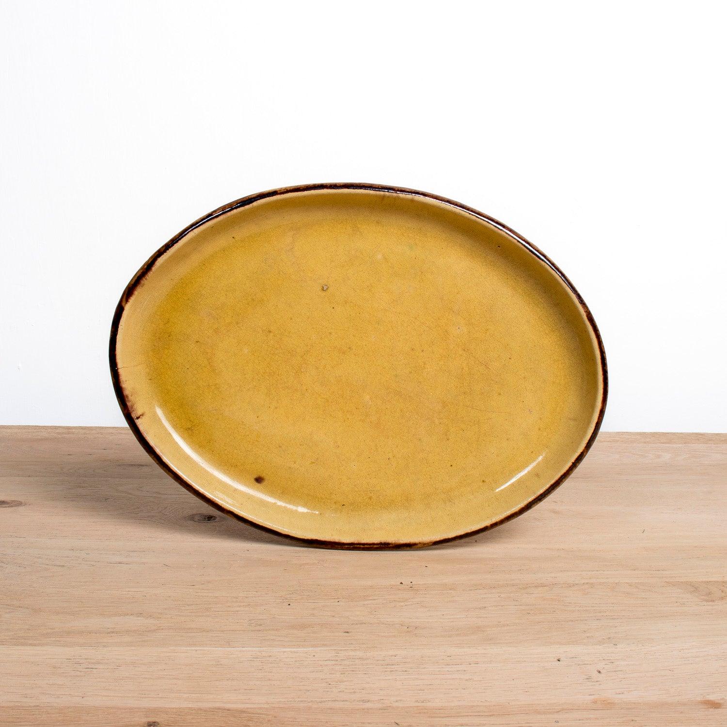 Un grande piatto ovale vintage in yellowware proveniente da Dieulefit, un pittoresco villaggio nel sud-est della Francia con una tradizione ceramica di oltre 2.000 anni. Questo piatto di terracotta rustico ma raffinato, realizzato a mano intorno