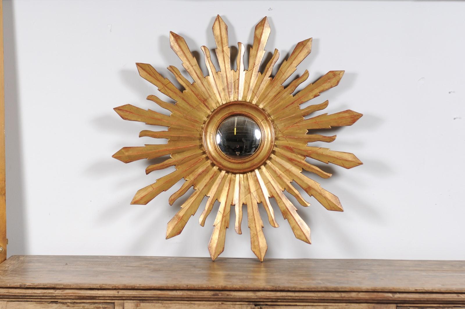 A large vintage French sunburst mirror from the mid-20th century, with convex mirror and radiating rays. This captivating large vintage French sunburst mirror from the mid-20th century radiates charm and elegance. Centered with a convex mirror that