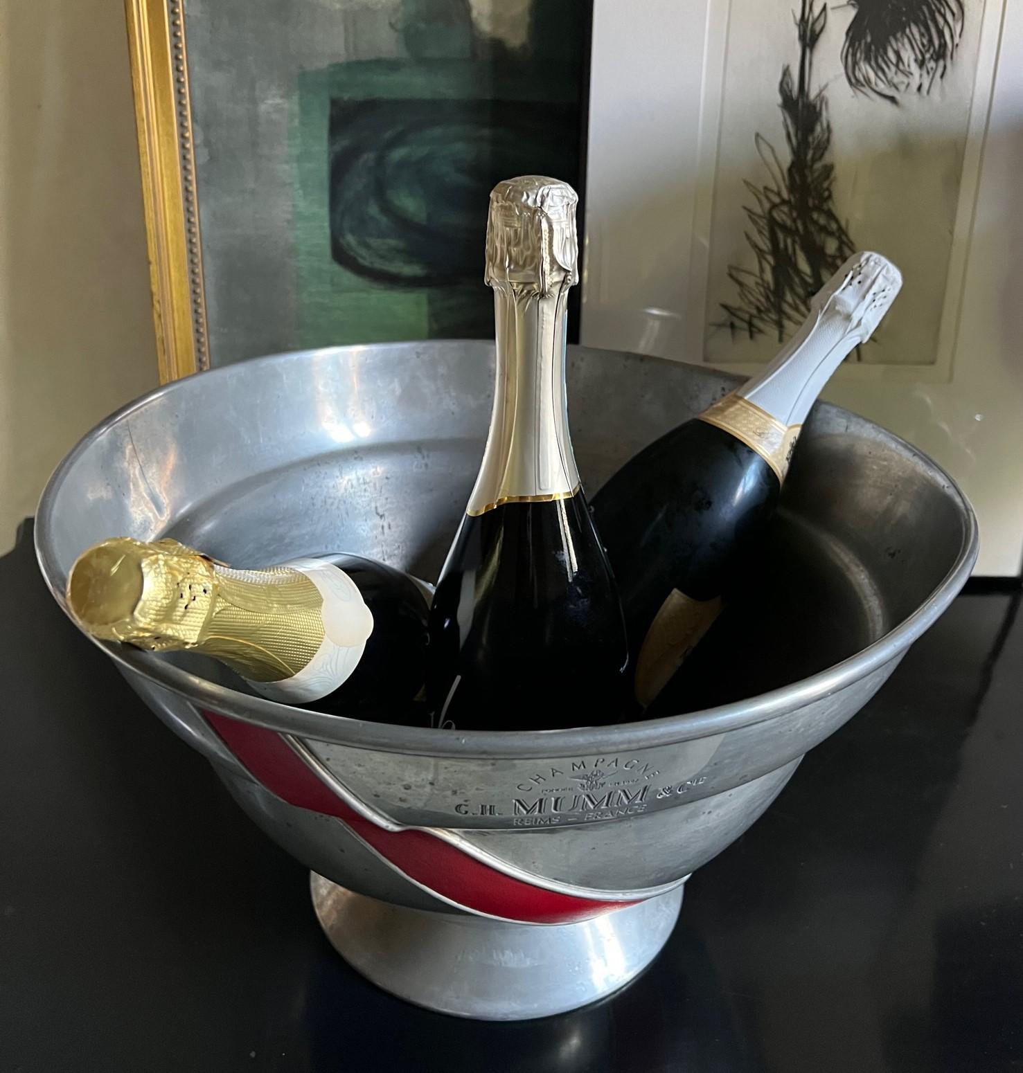 Large vintage pewter champagne bucket made by Etain in France for the Mumm champagne house. Includes a red leather diagonal stripe.

Impressed on the front: Champagne Fondee En 1827 G.H. Mumm & Cie Reims-France, with the eagle emblem.

Famous