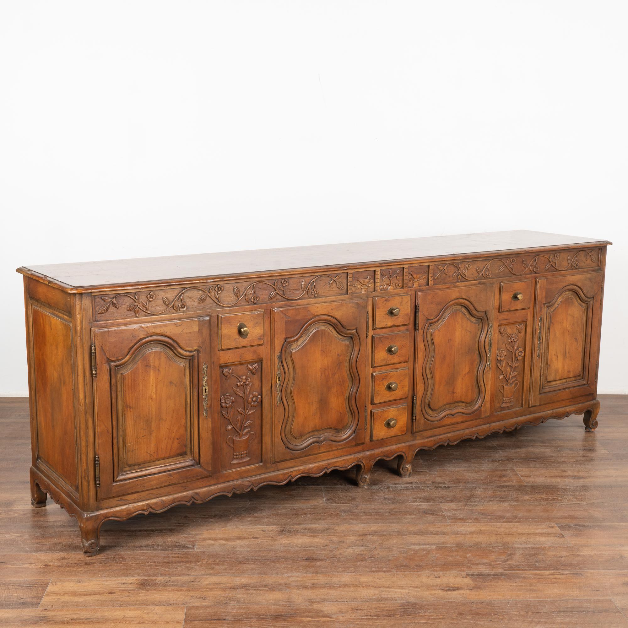 Large French walnut sideboard with traditional carved flower and vine details. At 8' long, this will serve as an impressive buffet resting on carved cabriolet feet.
Note the unique configuration of drawers both interior and exterior allowing for