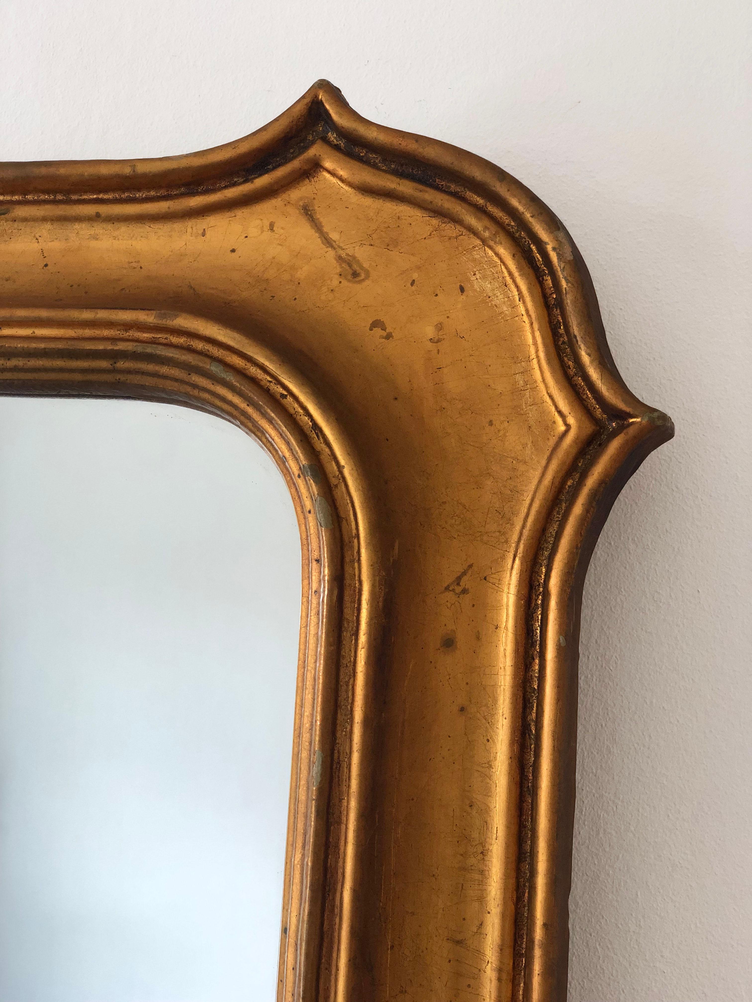 Vergoldeter Vintage-Spiegel aus Belgien, inspiriert vom Stil Napoleons III., mit breitem Holzrahmen und dezenten Schultern an den Ecken. Das Goldfinish hat eine natürliche Patina, die ihm ein warmes und authentisches Aussehen verleiht.

Objekt: