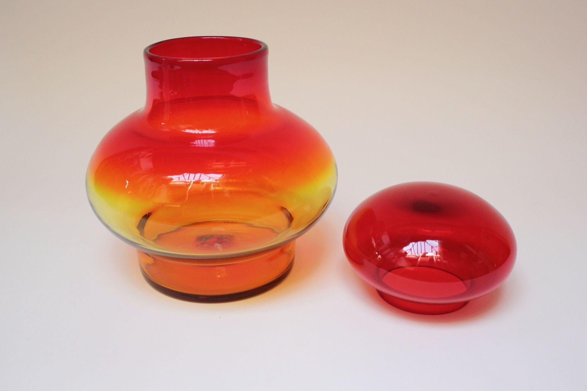 Großes mundgeblasenes Glas mit bernsteinfarbenem/tangerinenfarbenem Deckel, entworfen von John Nickerson für Blenko (Modellnummer 7328).
Dieses Modell erschien erstmals im Blenko-Katalog von 1973 und wurde nur zwei Jahre lang produziert. Seltenes