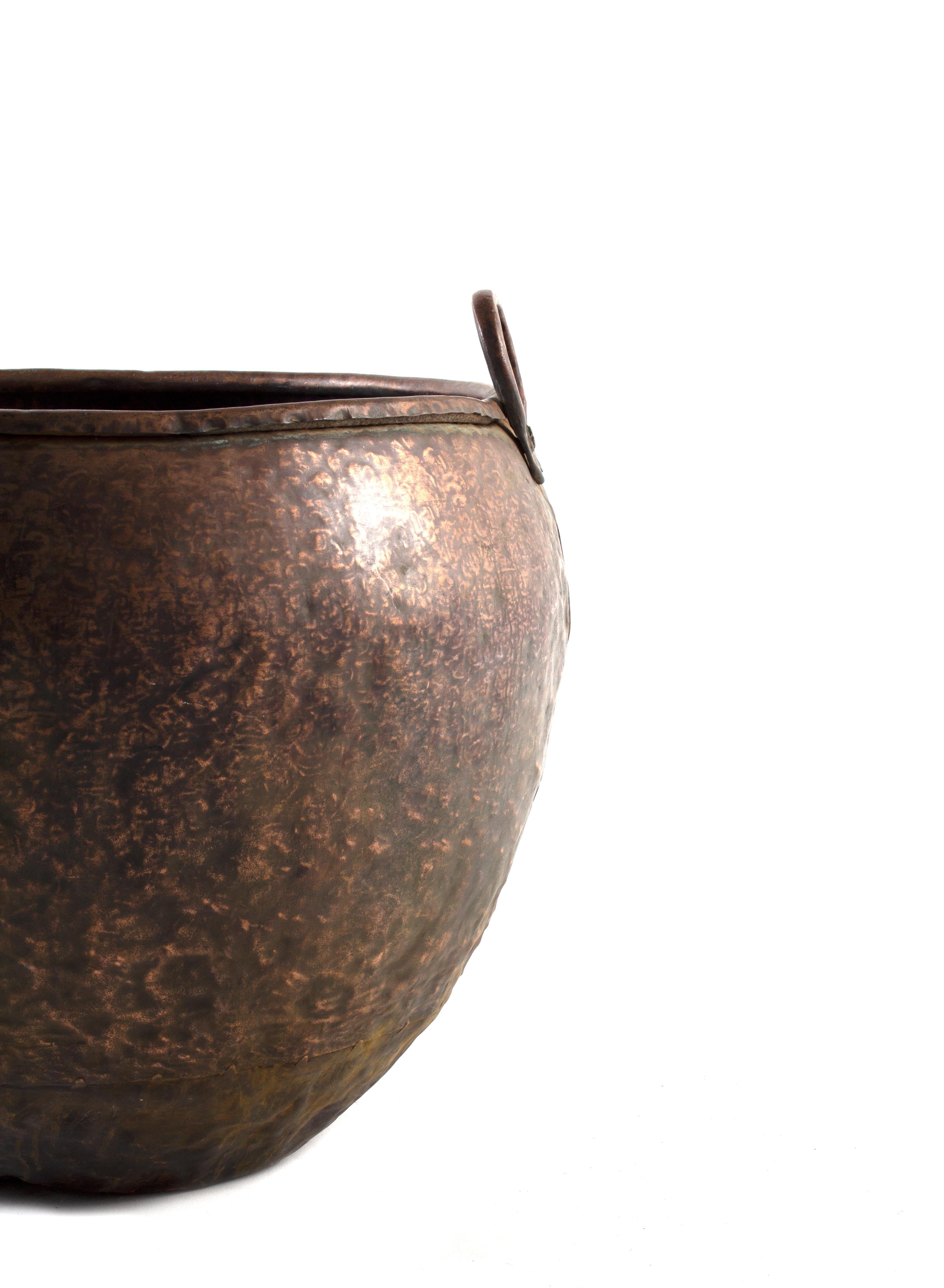 This Large Vintage Hammered Copper South Asian Textile Pot adds beautiful texture to any space. Crafted from a single piece of hammered copper, the lid features a raised center section with a decorative pattern. The round silhouette is perfect for