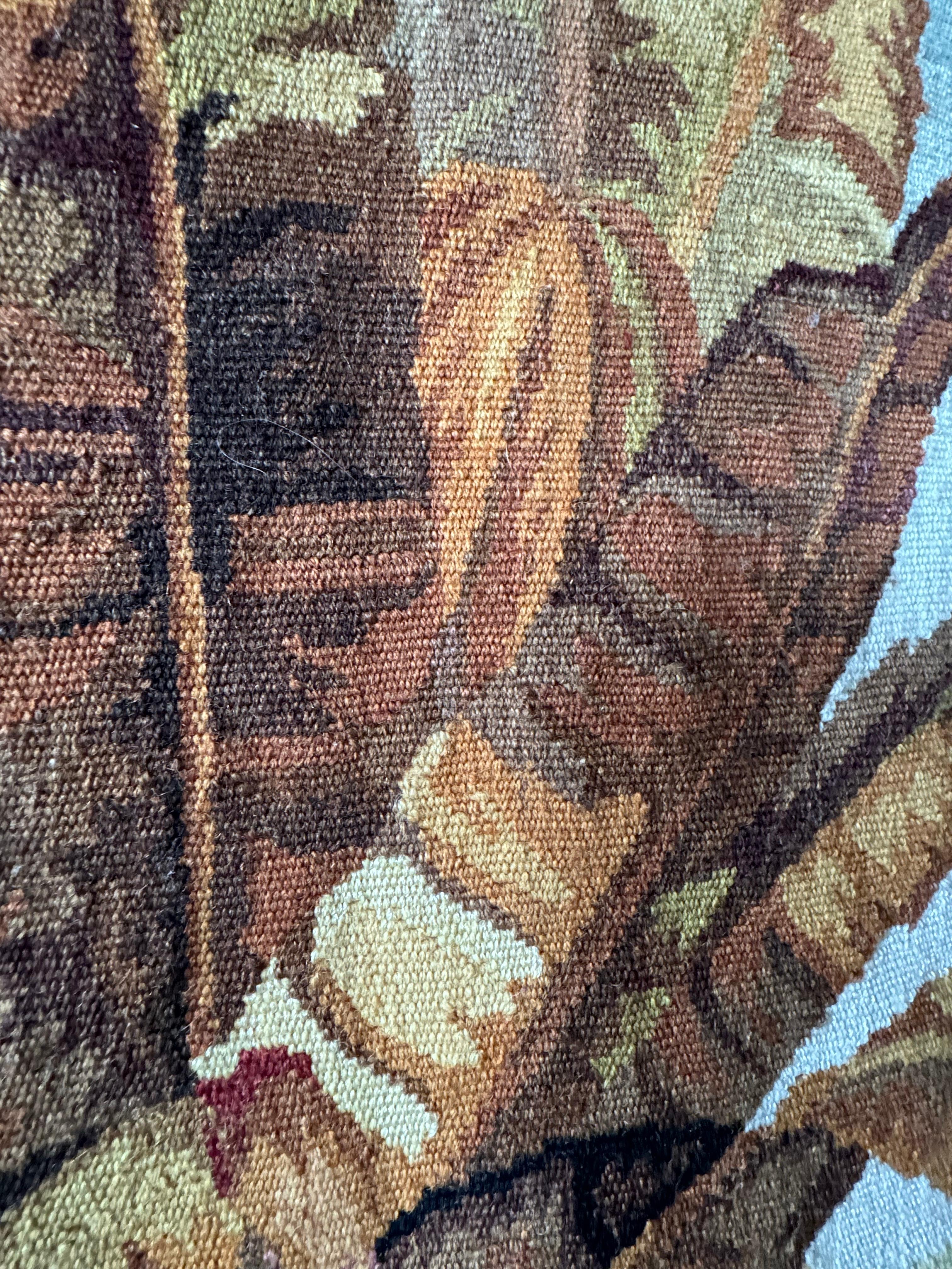 This stunning, handwoven tapestry showcases a captivating chinoiserie scene, featuring two large birds, a majestic palm tree, a serene lake, mountains, and an elegant bridge. The artistry is remarkable, with vibrant golds, oranges, reds, and saffron