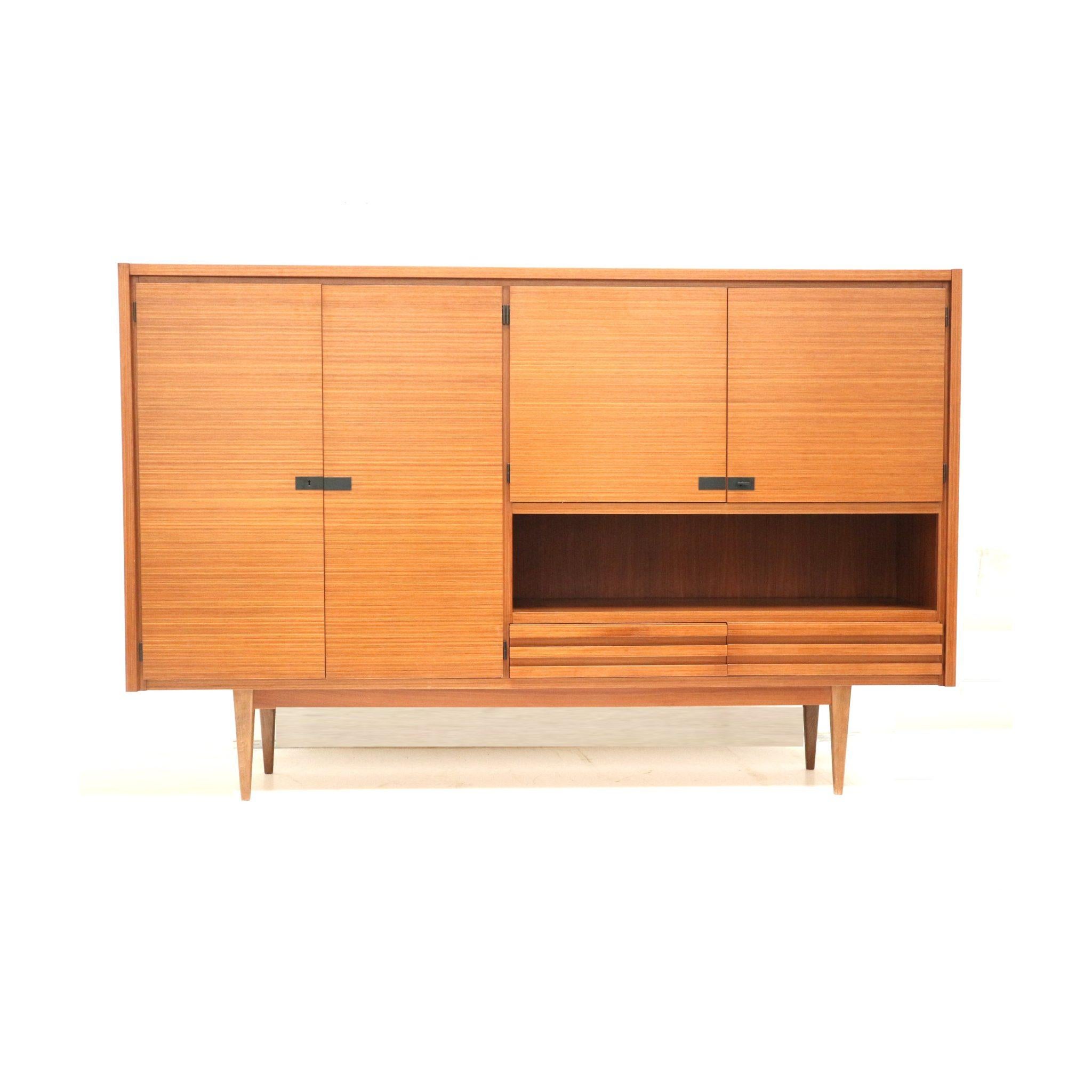 Discover this stunning large vintage highboard, crafted from beautiful teak wood in the 1960s. With its sleek lines and warm tones, this piece adds a timeless charm to any interior. The generous storage space makes it perfect for displaying your