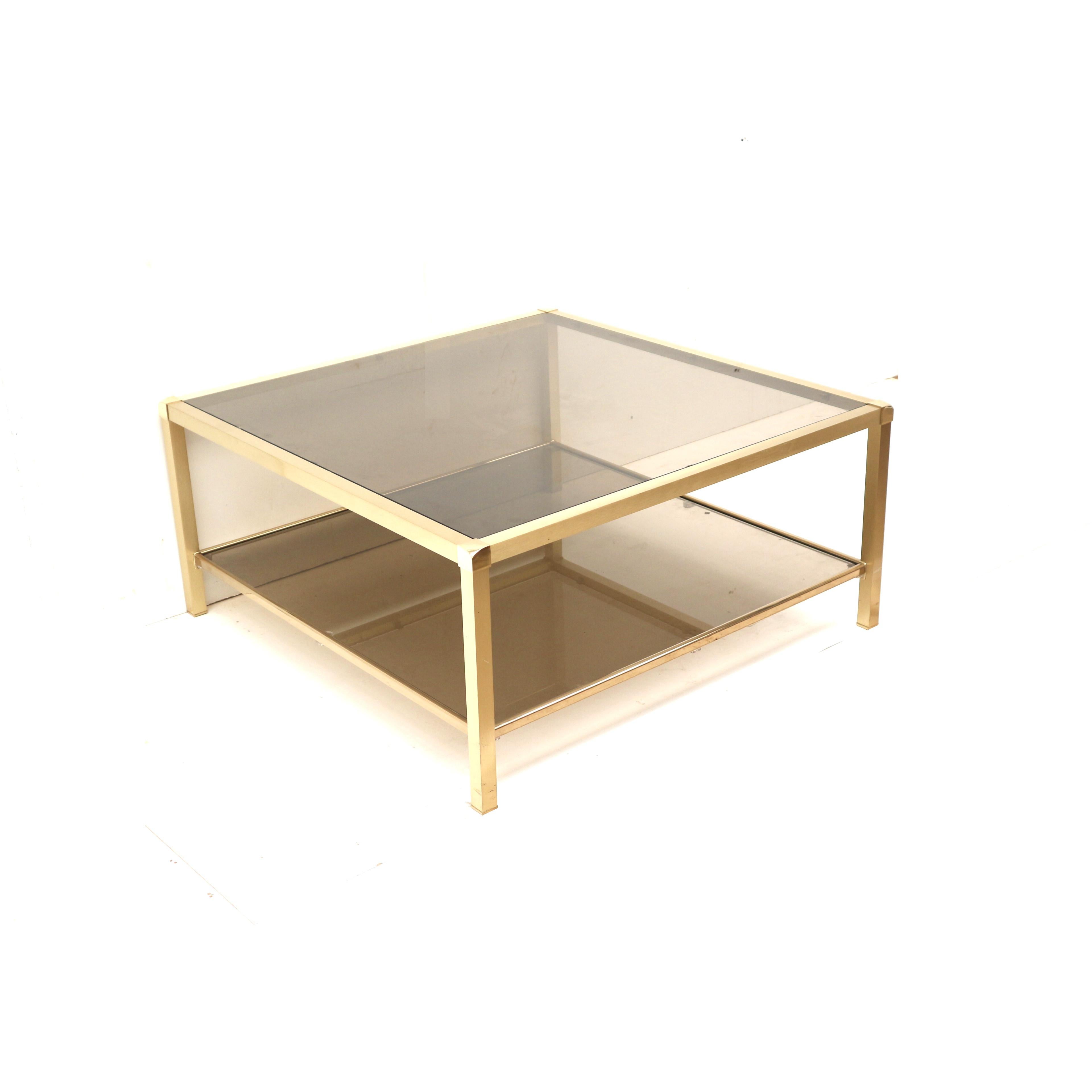 Grande table basse vintage Hollywood Regency en laiton et verre fumé des années 1970.

Dimensions :
Largeur : 97 cm
Profondeur : 97 cm
Hauteur : 45 cm

La table présente des signes mineurs d'utilisation correspondant à son âge.