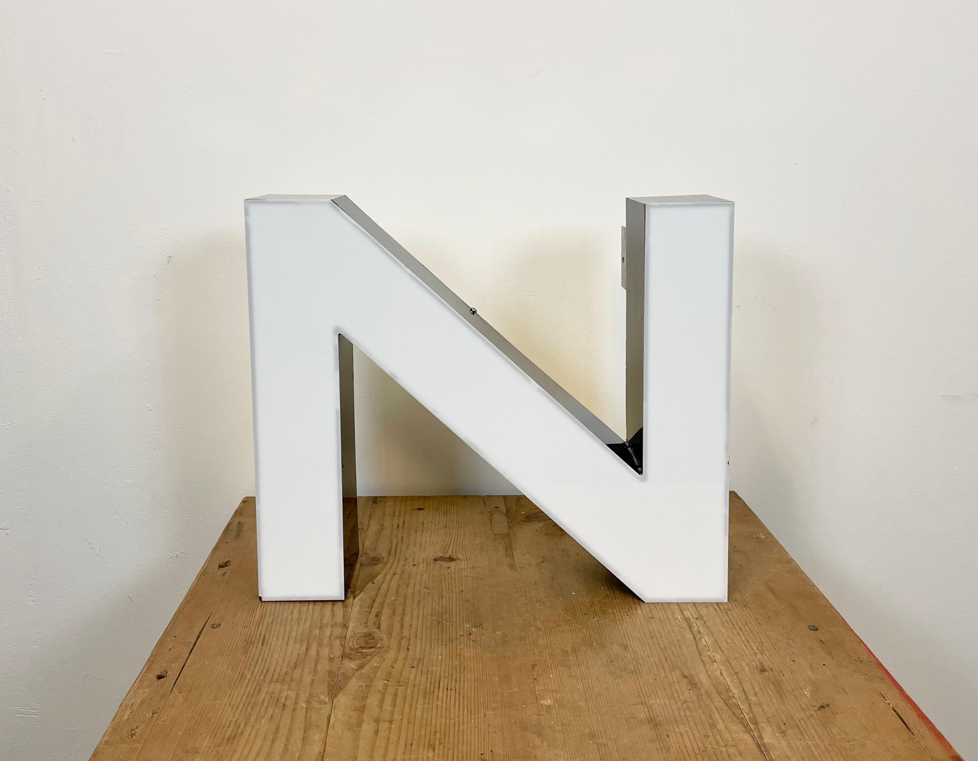 This vintage industrial illuminated letter  N was made in United Kingdom during the 1980s and comes from an old advertising banner BENTLEY It features a black metal body and a white plexiglass cover. It is equipped with a LED strip. The letter can