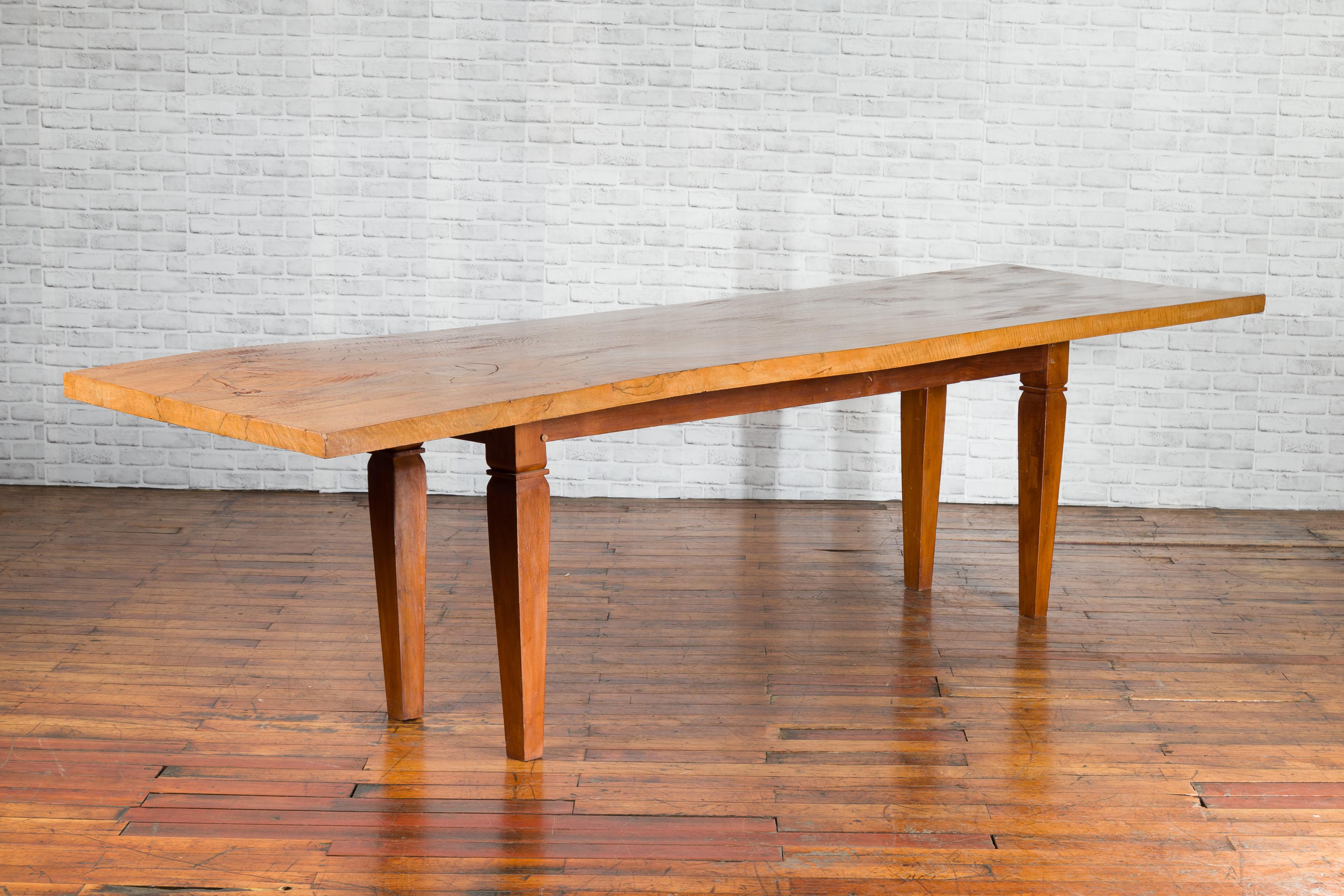 A vintage Indonesian large dining table from the mid 20th century, with mango wood top and tapered legs. Created in Indonesia during the midcentury period, this large dining table features a rectangular single plank mango wood top with nicely