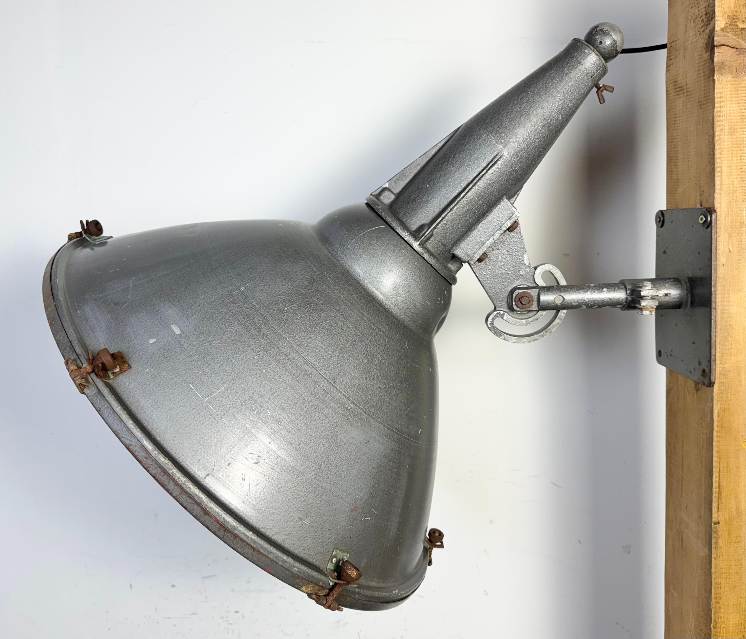 Vintage Industrial factory hall wall spotlight with adjustable angle made by Elektrosvit in former Czechoslovakia during the 1970s. The spotlight has aluminium shade,a cast aluminium top,a clear glass cover and an iron wall mounting. The porcelain