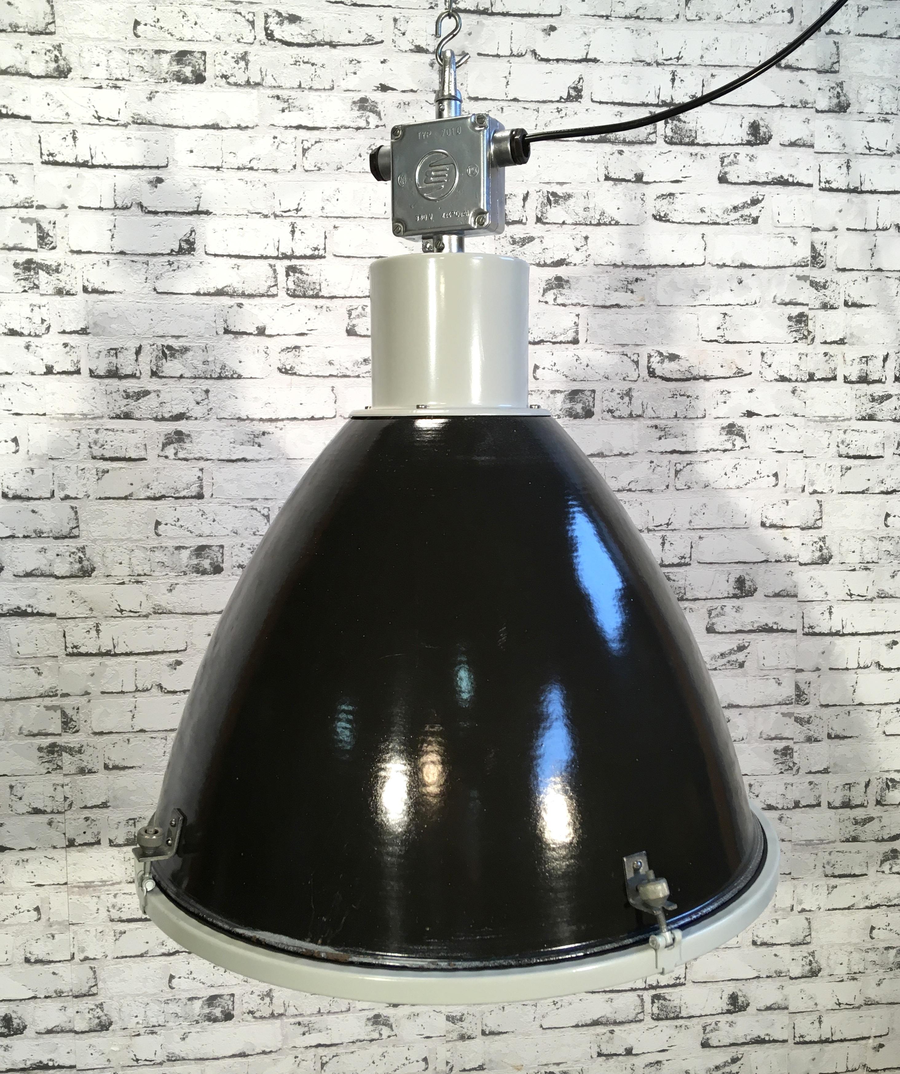This steel black enamel pendant lamp was designed in the 1960s and produced by Elektrosvit in the former Czechoslovakia. It features a grey metal top with cast aluminium box, black enamel shade, white enamel interior, and clear glass cover.
Lamp is