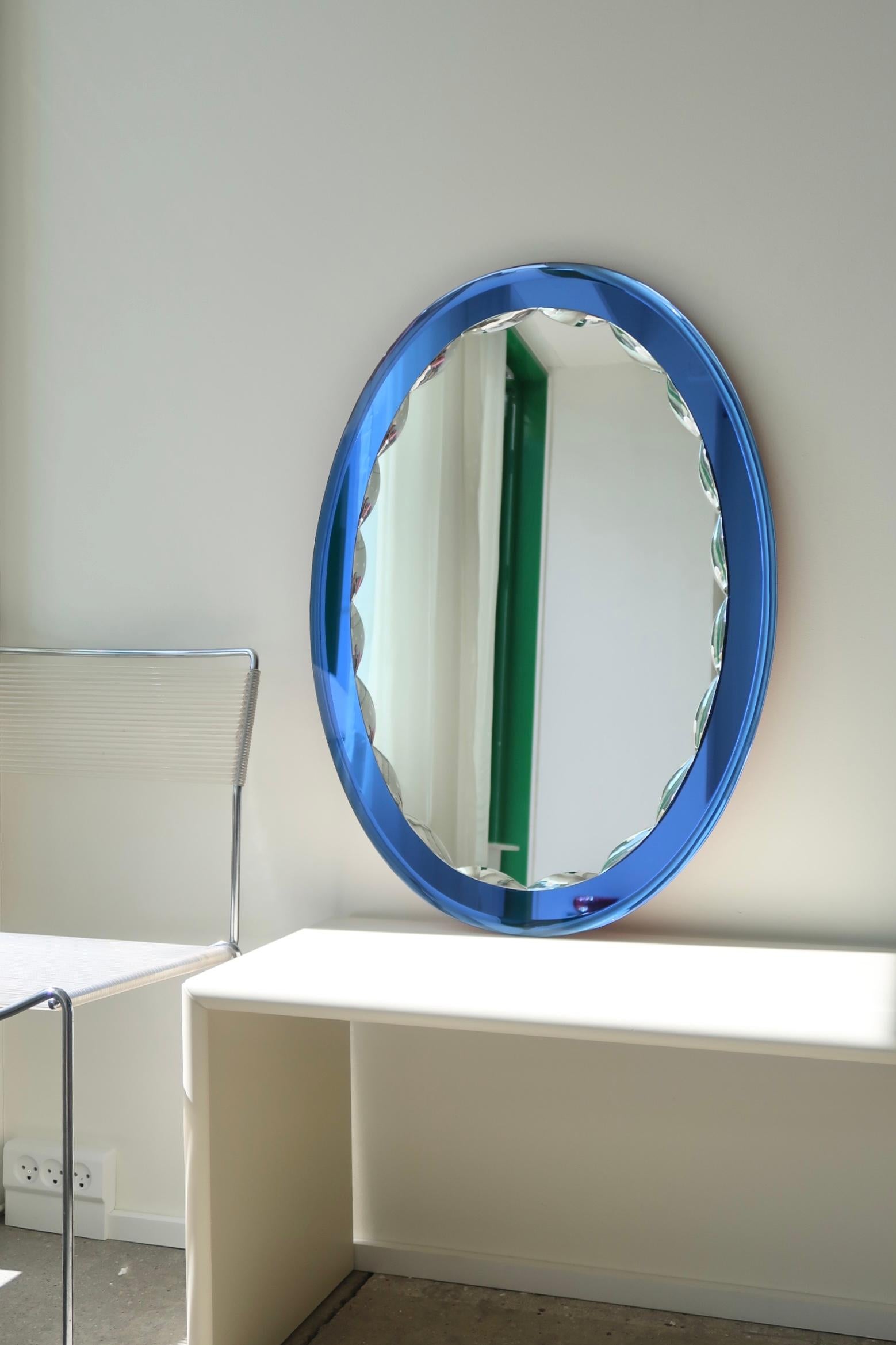Large vintage Italian mirror in oval faceted glass with sapphire blue rim. Handmade in Italy, 1970s. The glass appears without chips/damage with minimal traces of use. 
Measures 57.5x81 cm.

