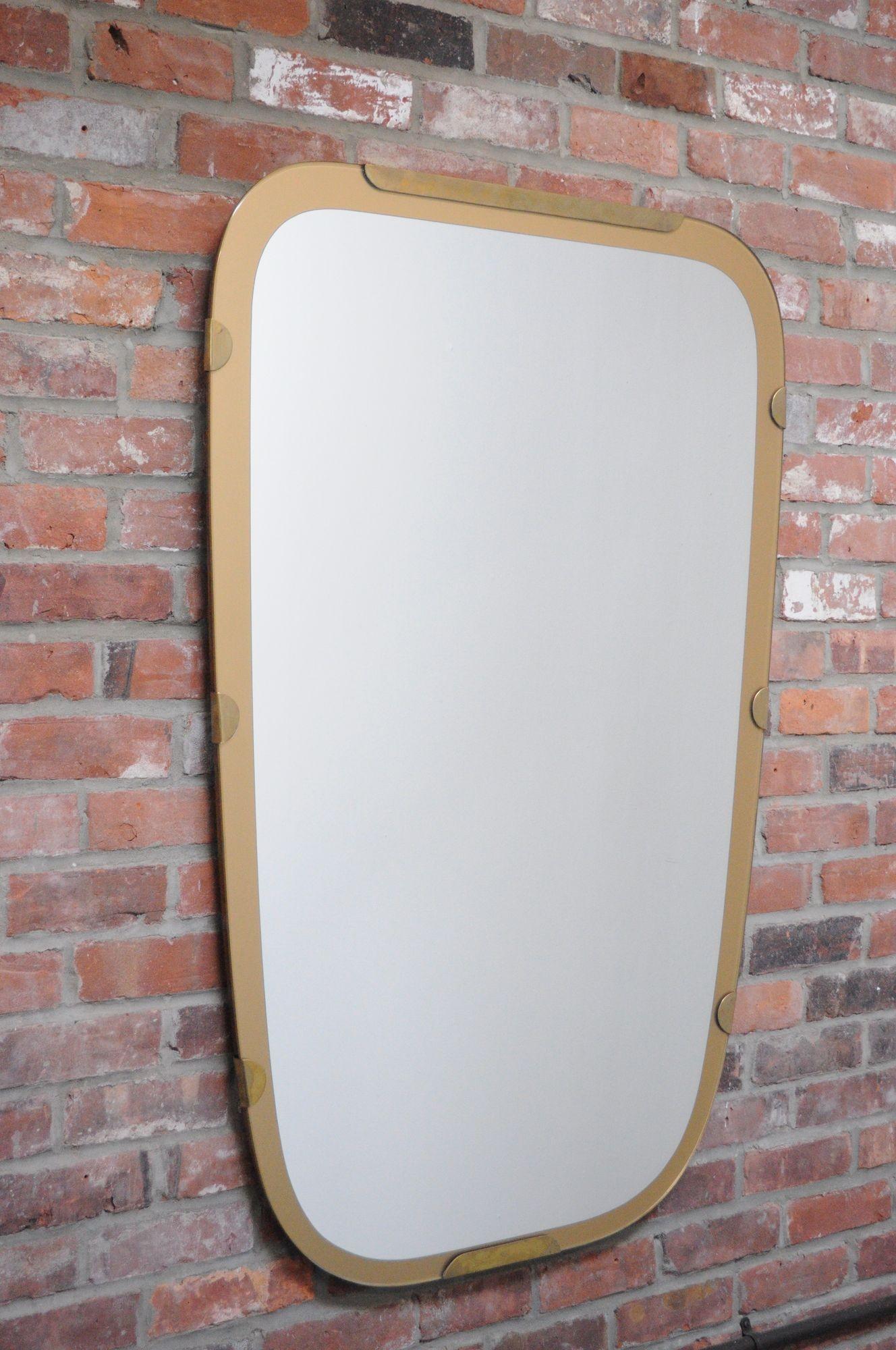 Substantial, sculptural wall mirror composed of a sold Italian walnut backing with gold anodized aluminum trim and brass accents/hardware (ca. 1960, Italy).
Extremely well made with careful attention to quality, durable materials and stylistic