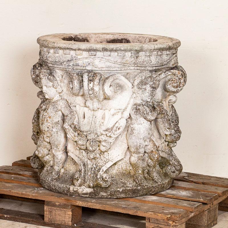 This Italian cast concrete planter is encircled with traditional cherubs. Large and round, this is planter can be used dramatically for flowers, topiary or even a tree. The planter has aged well and has a welcoming, worn patina revealed in the