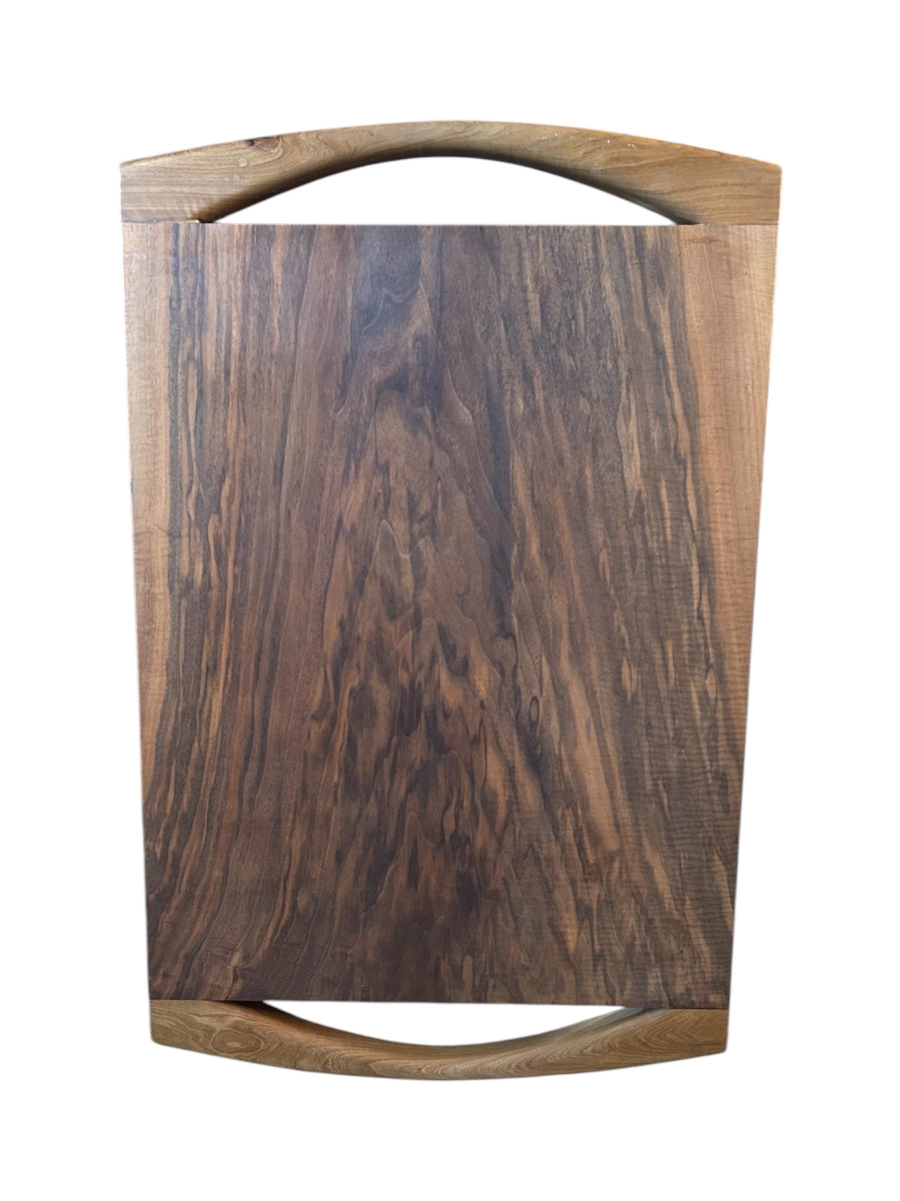 Crafted in Italy circa 1970s, this impressive vintage chopping block is made from solid walnut, showcasing a rich grain pattern and warm, earthy tones. Its standout feature is the pair of beautifully curved handles at each end, smoothly sculpted