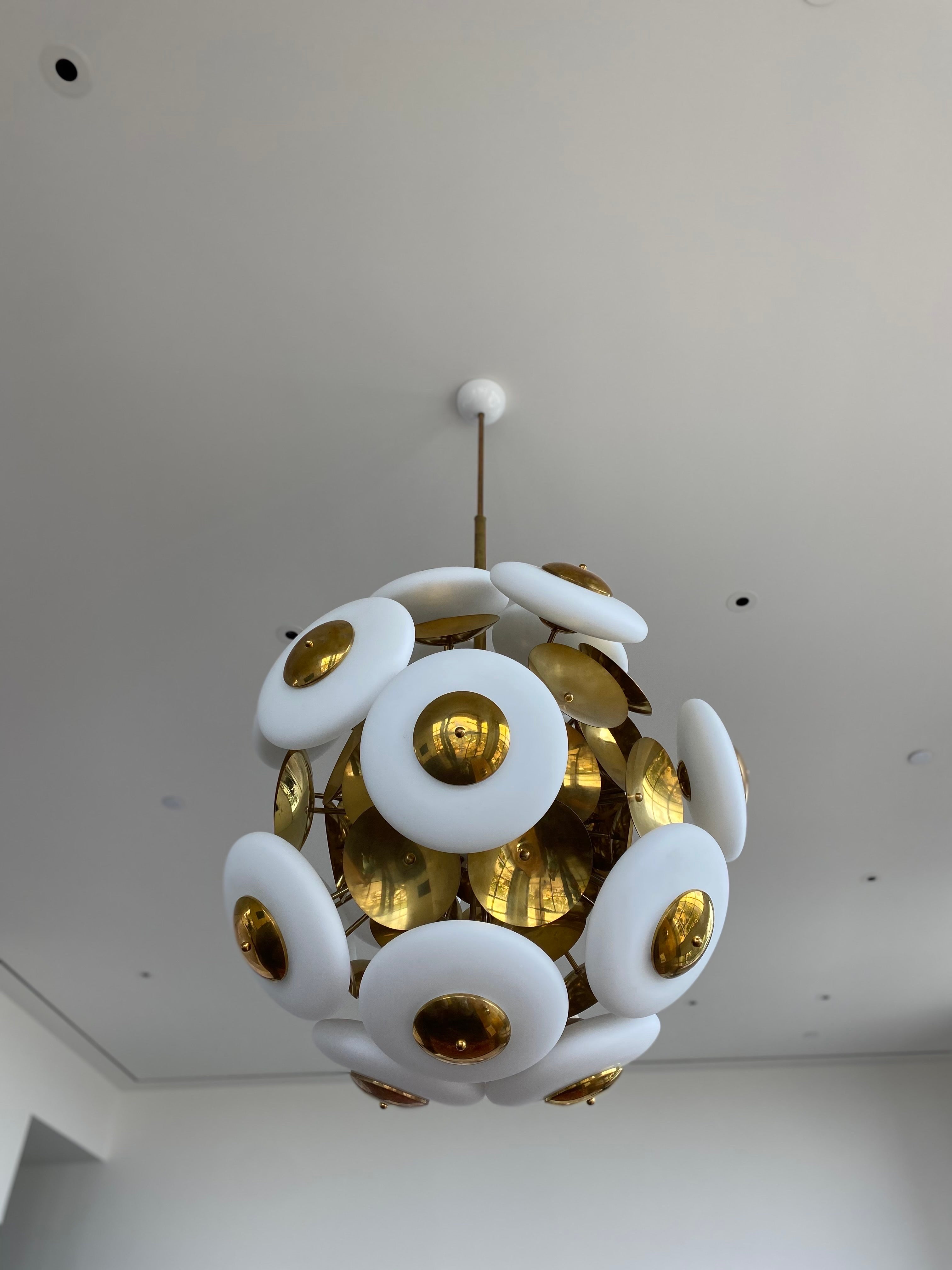 Impressive large Italian Cielo sputnik chandeliers are sold separately but can be sold as a pair. Discs consist of a matte white finish, and are made of Murano glass on a brass frame and brass discs that hold the Murano glass. The Murano glass can