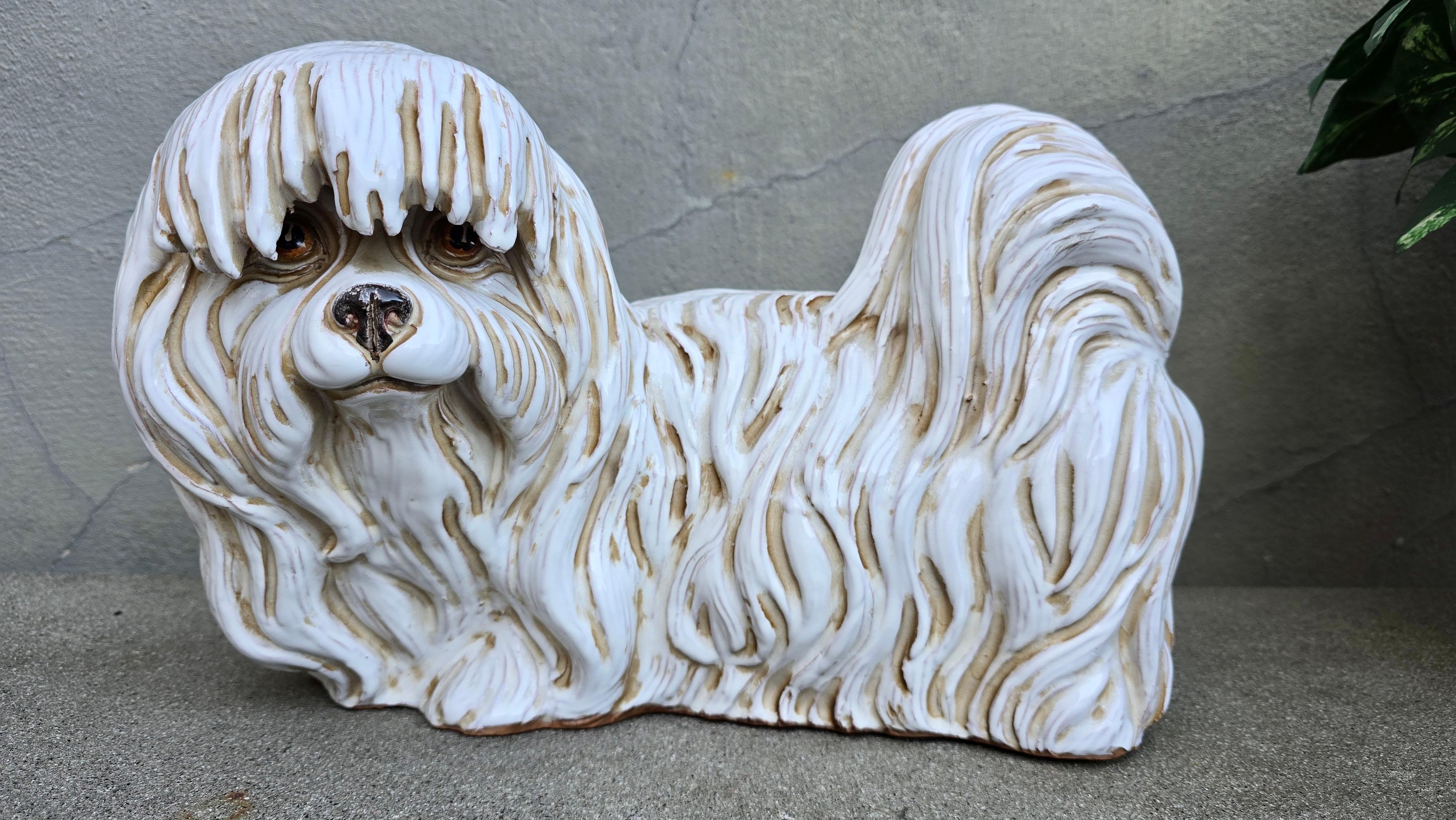 This charming vintage Italian glazed terracotta dog statue has been made in the form of a Maltese. The Maltese's fur bears its characteristic white color along with tan accents that serve to highlight the individual strands of its silky coat. The