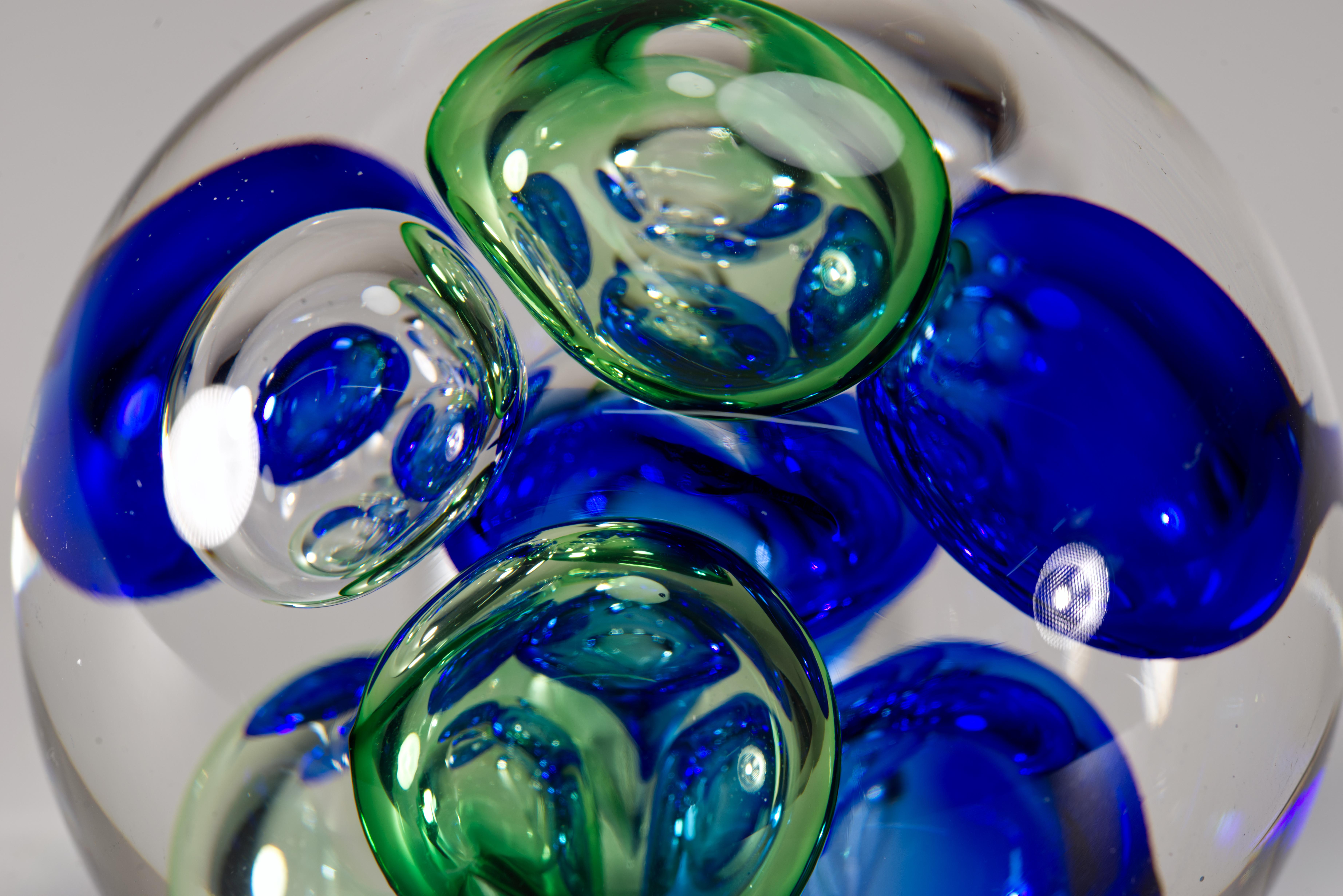  Ce presse-papier vintage impressionnant présente un groupement abstrait de grandes bulles contrôlées en verre transparent et coloré bleu cobalt et vert gazon. Le motif central est enchâssé dans du verre transparent selon la technique sommerso. La