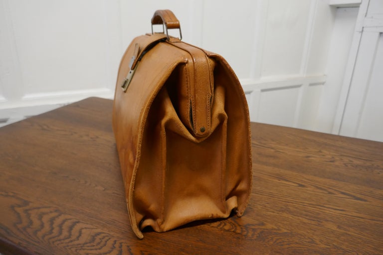 Large vintage leather brief case, doctors bag.

This a superb quality piece, it is made in heavy quality tan pig skin, with brass working catch, but no key. The Bag has a leather handle, and the interior is divided into three sections and lined in