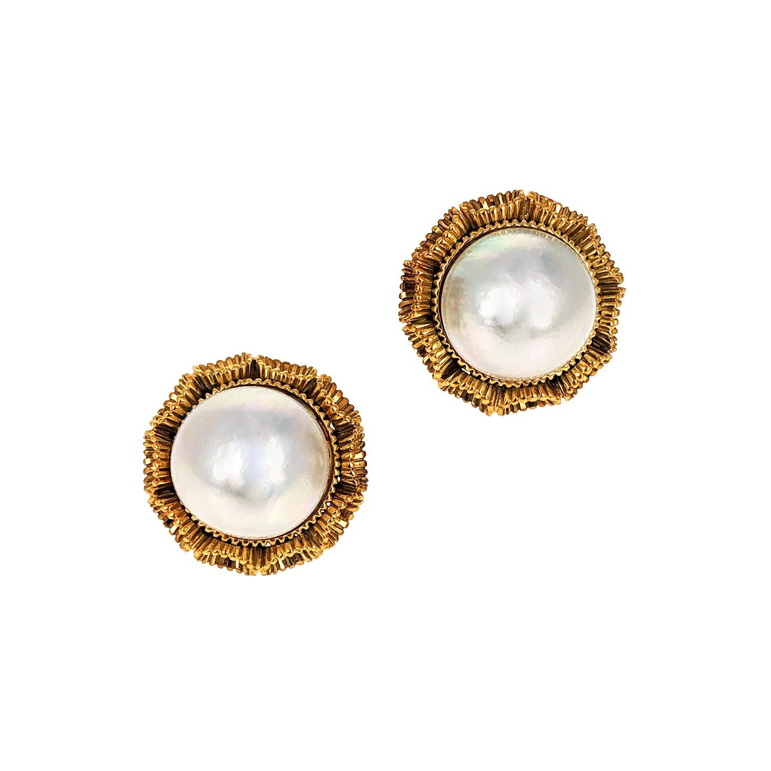 These clip earrings are set with two large white mabe pearls in textured fluted 18 karat yellow gold mountings. The pearls have very good luster and great surface quality. Each is in wonderful condition and very chic. They were made circa 1980.