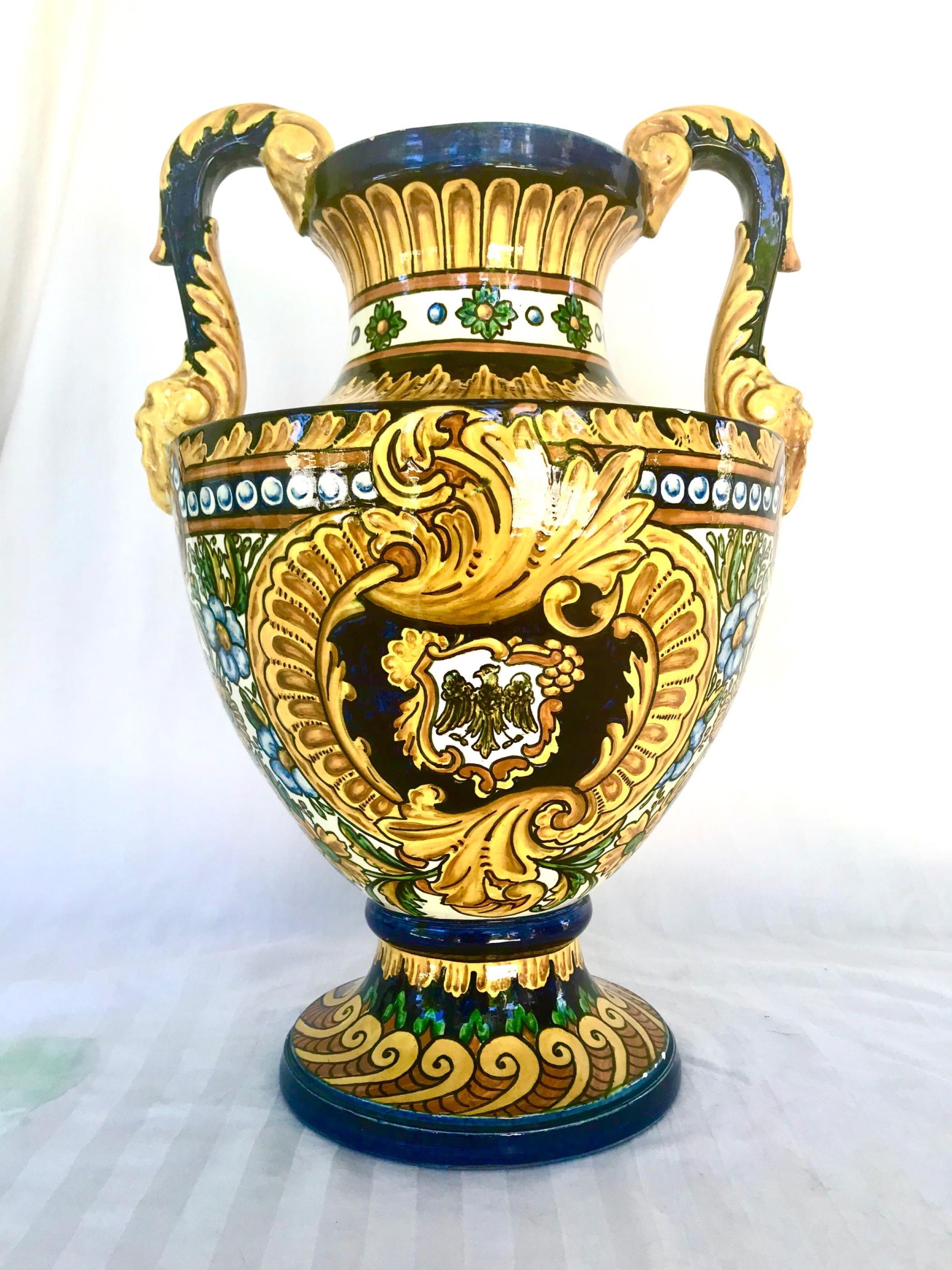 Large vintage Mediterranean Majolica two handled urn.

This fabulous vintage bulbous urn is hand decorated with yellow Renaissance Medici style motifs against a dark blue background. Two C-scroll handles are ornate with hand painted acanthus leaf