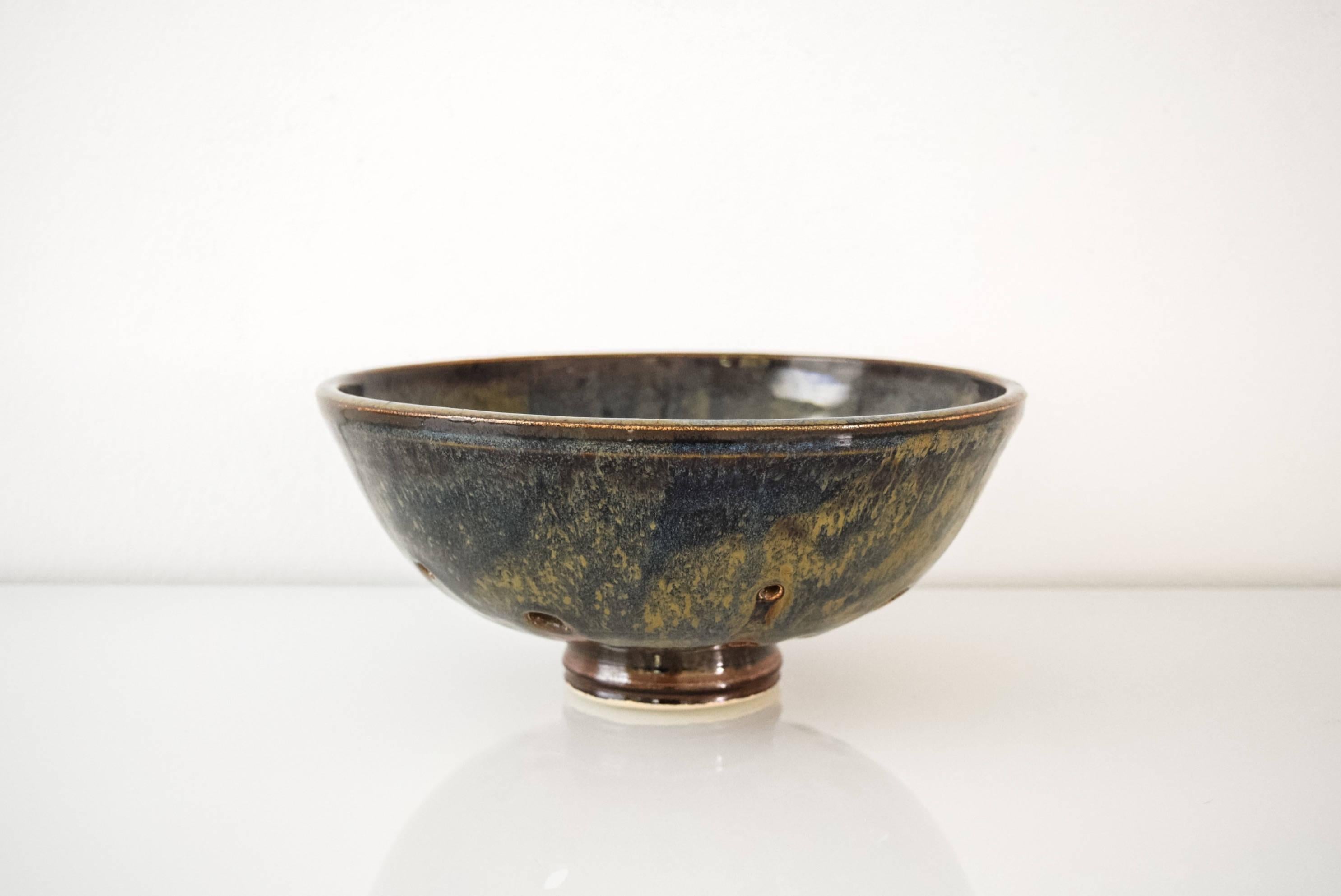 • Vintage Mid-Century Modern ceramic pottery bowl, circa 1960.
• Beautifully handcrafted.
• Distinctive modernist design with accent holes, centre rings and pedestal base.
• Gorgeous coloring in natural shades of green, blue, rust and