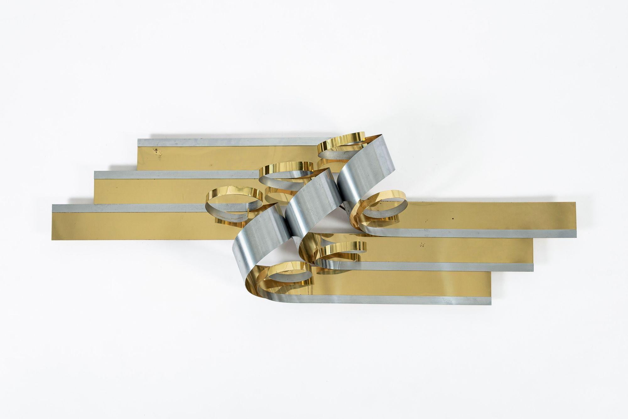 Diese Vintage Mid Century Modern Curtis Jere Metallband Wand Kunst hängende Skulptur verfügt über kontrastierende Messing und Silber getönten Metallstreifen in eine schöne schlanke und stilisierte Band Form verdreht. Dieses Stück ist groß und gut