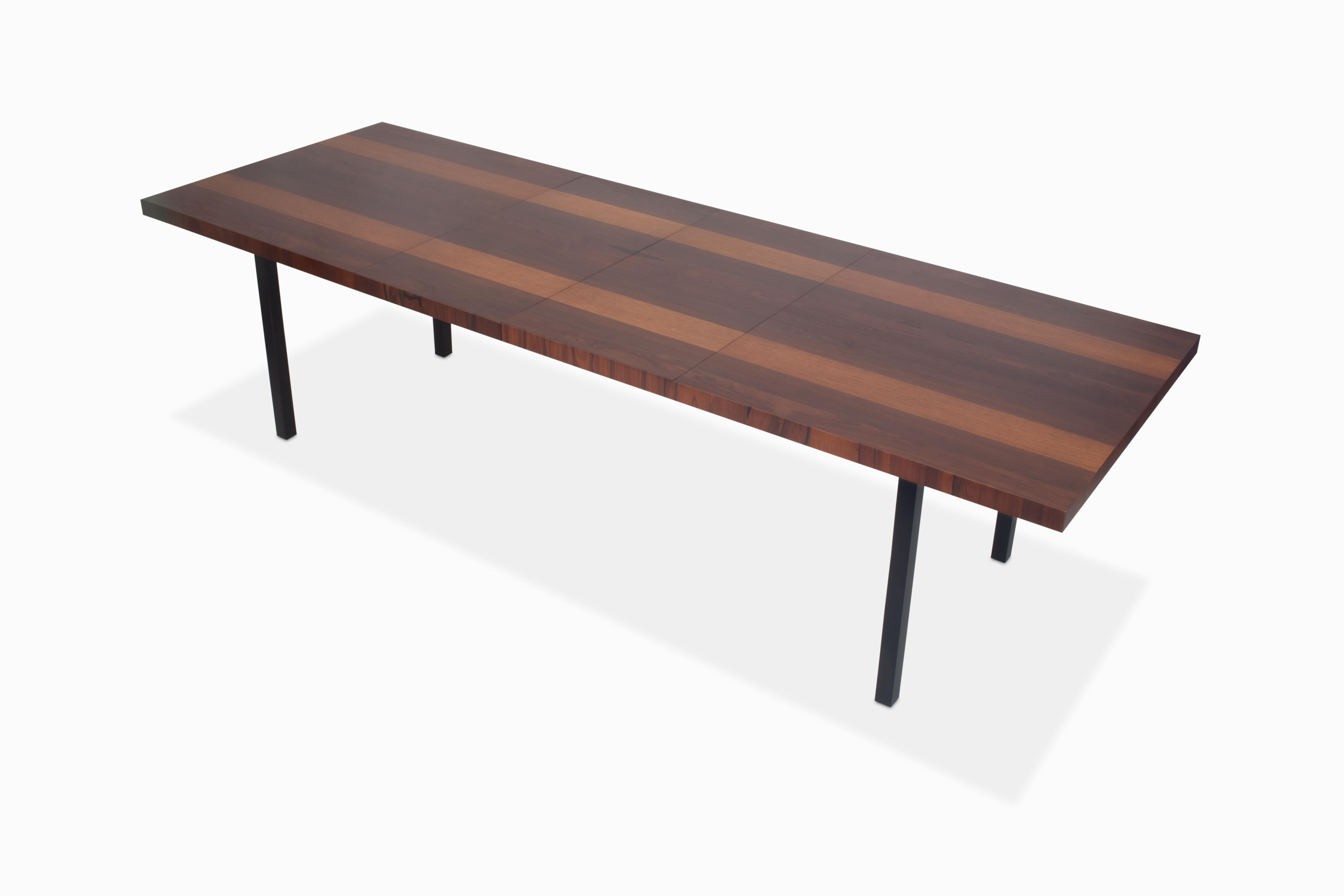 Here is a large multi-wood dining table designed by Milo Baughman for Directional. It is comprised of rosewood, walnut and ash veneers atop a very sturdy black lacquered base. Fully expanded, this table spans 112