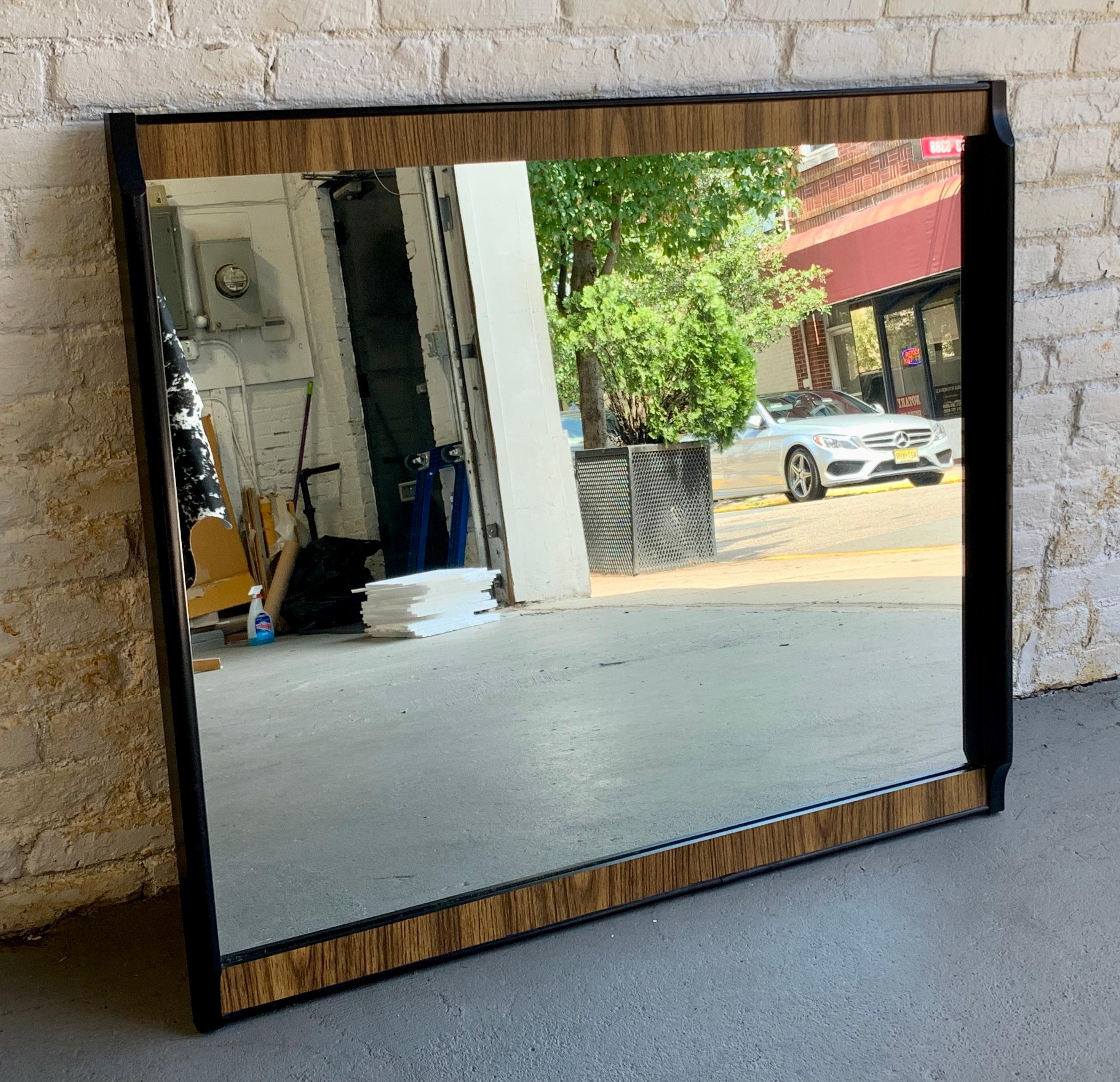 Large Mid century modern mirror by Kent Coffey's Teakway line, circa 1960's. This unique mirror features an ebonized and woodgrain laminate frame. Lovely vintage condition with some wear from age and use (as pictured) and a break to the bottom edge