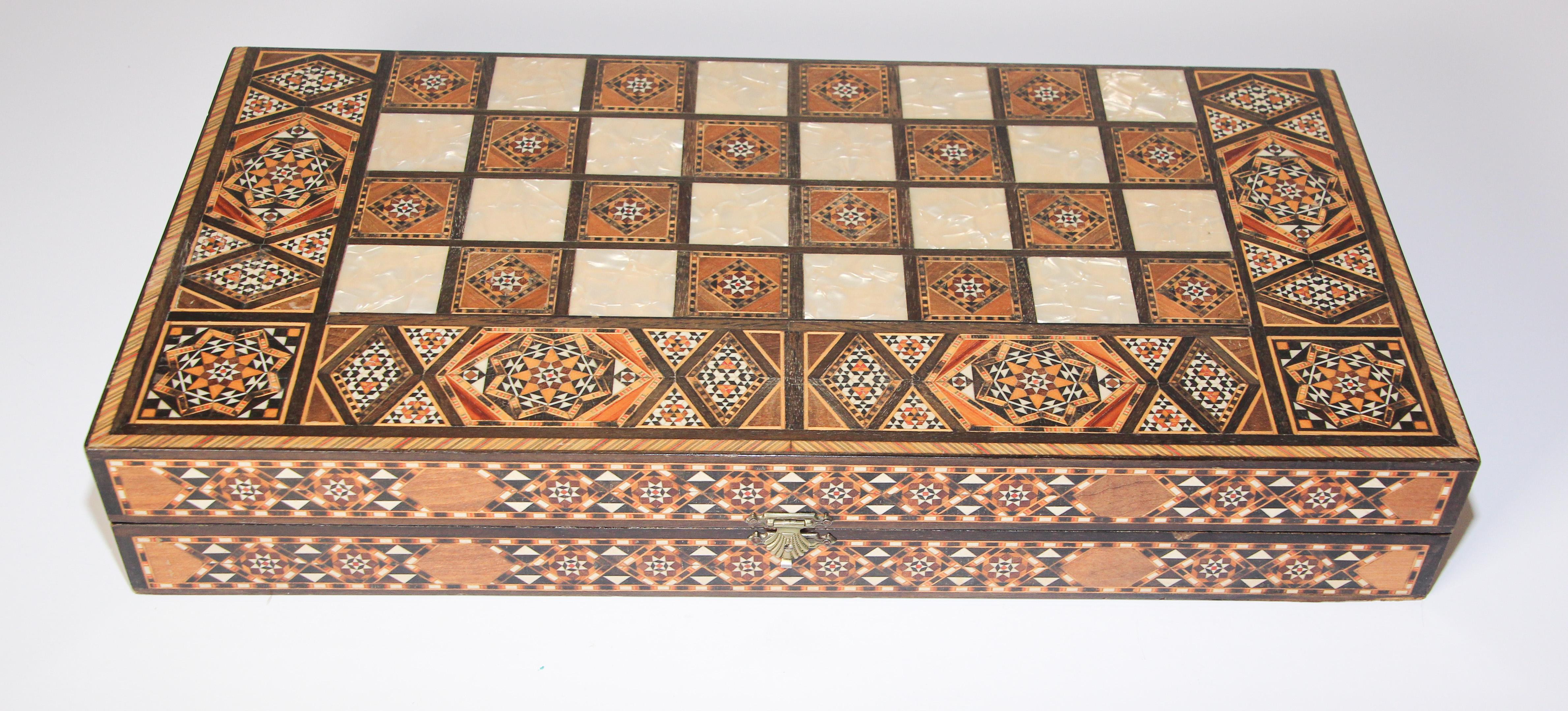 Large vintage midcentury Syrian inlaid with mother of pearl mosaic backgammon and chess game.
Great inlaid micro mosaic hinged marquetry game box features a chess and checker board on the exterior and backgammon board on the interior with all the