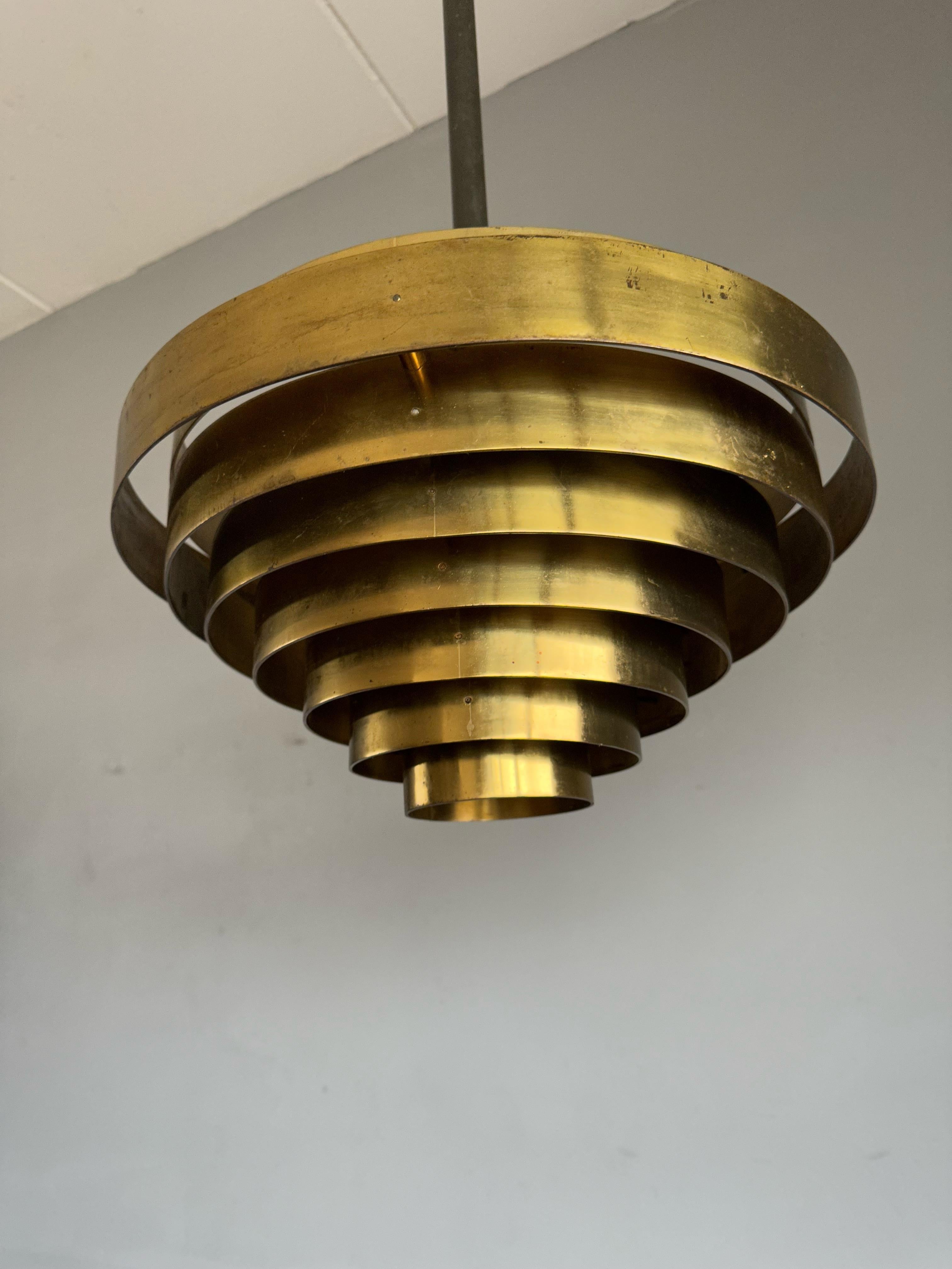 Rare design, three light pendants with layered brass shades.

If you are looking for a striking and extraordinary light fixture to grace your midcentury living or work space then these, European works of lighting art could be ideal for you. Mind