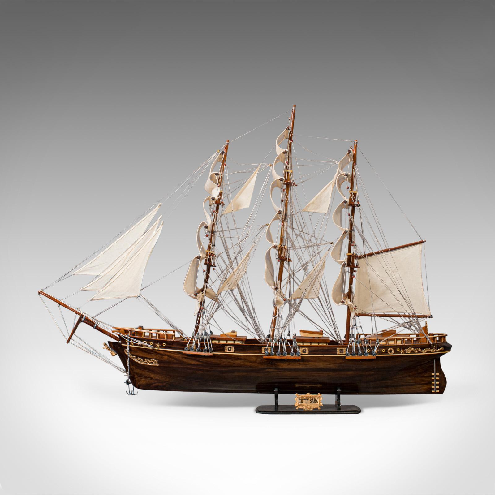 This is a large, vintage model of Cutty Sark. An English, mahogany collectible model ship with display Stand and dating to the 20th century.

Built in Scotland in 1869, the Cutty Sark was one of the last tea clippers, whilst being one of the