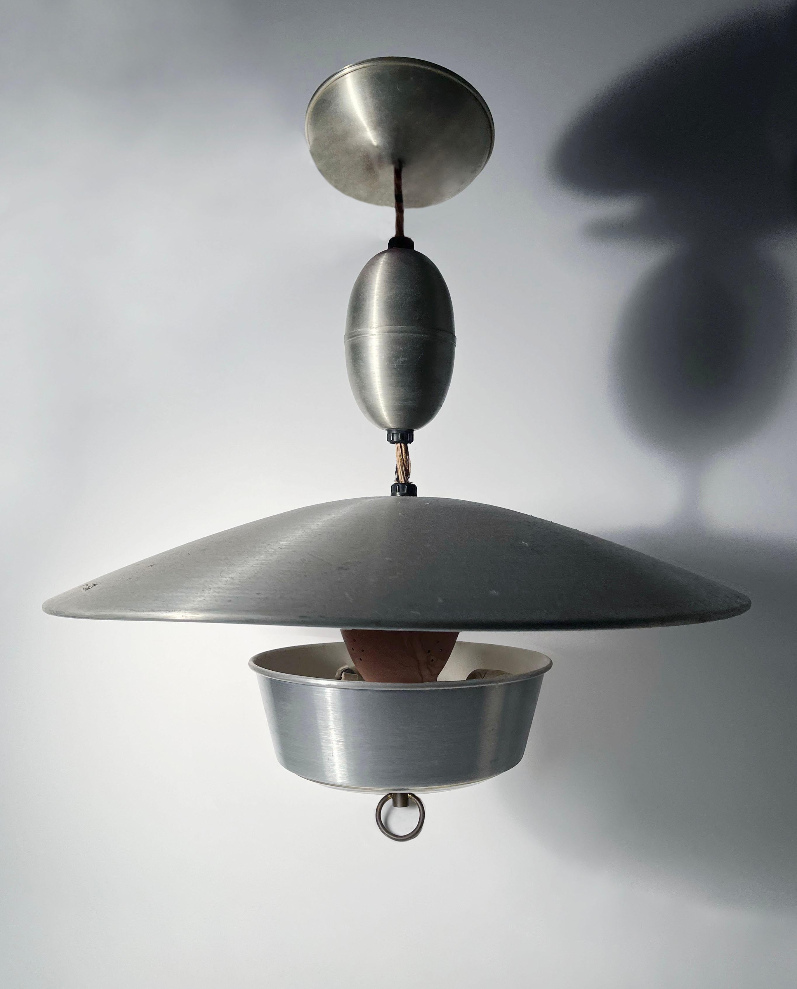 Very nice large scale Aluminum Pull Light Pendant.   Nice composition of aluminum parts to create a nice overall form to hang from a ceiling.  Ceiling Cap, Pull Cord Holder, Large reflector shade, a terracotta like painted diffuser, underside